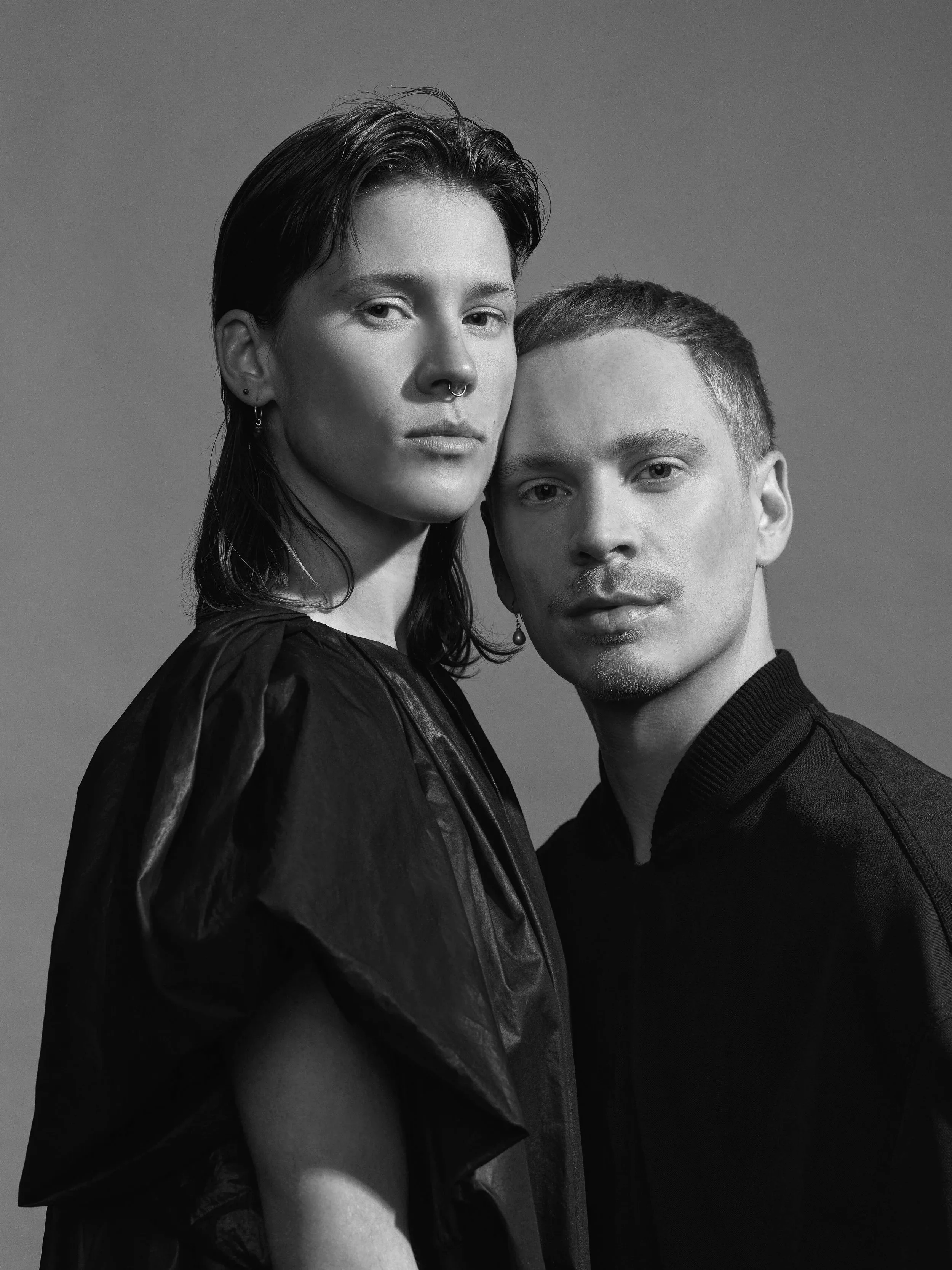 Black and white portrait of a woman and a man standing close together, both looking at the camera.