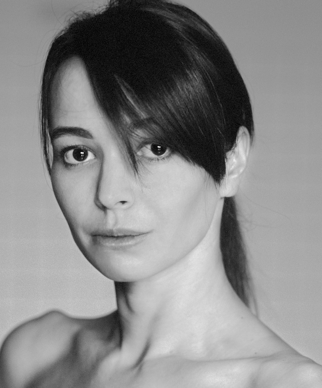 A black-and-white portrait of a woman with short, dark hair, looking directly at the camera with a neutral expression.