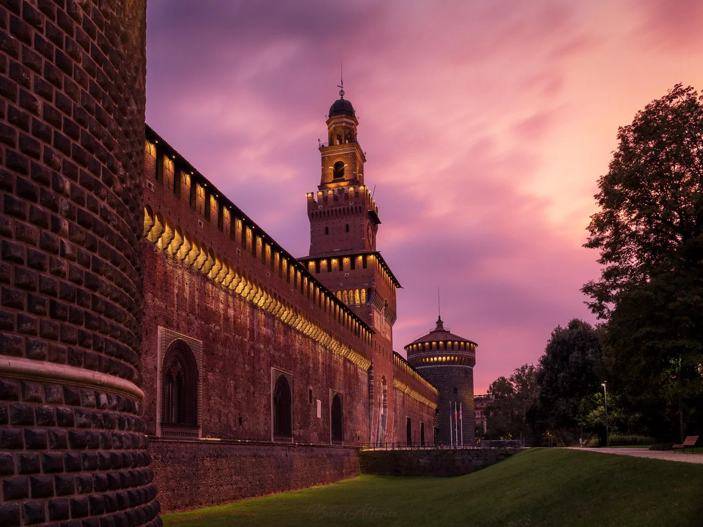 Long exposure capturing a soft pink sunrise over Castello Sforzesco in Milan, Italy, with gentle light illuminating the historic architecture.