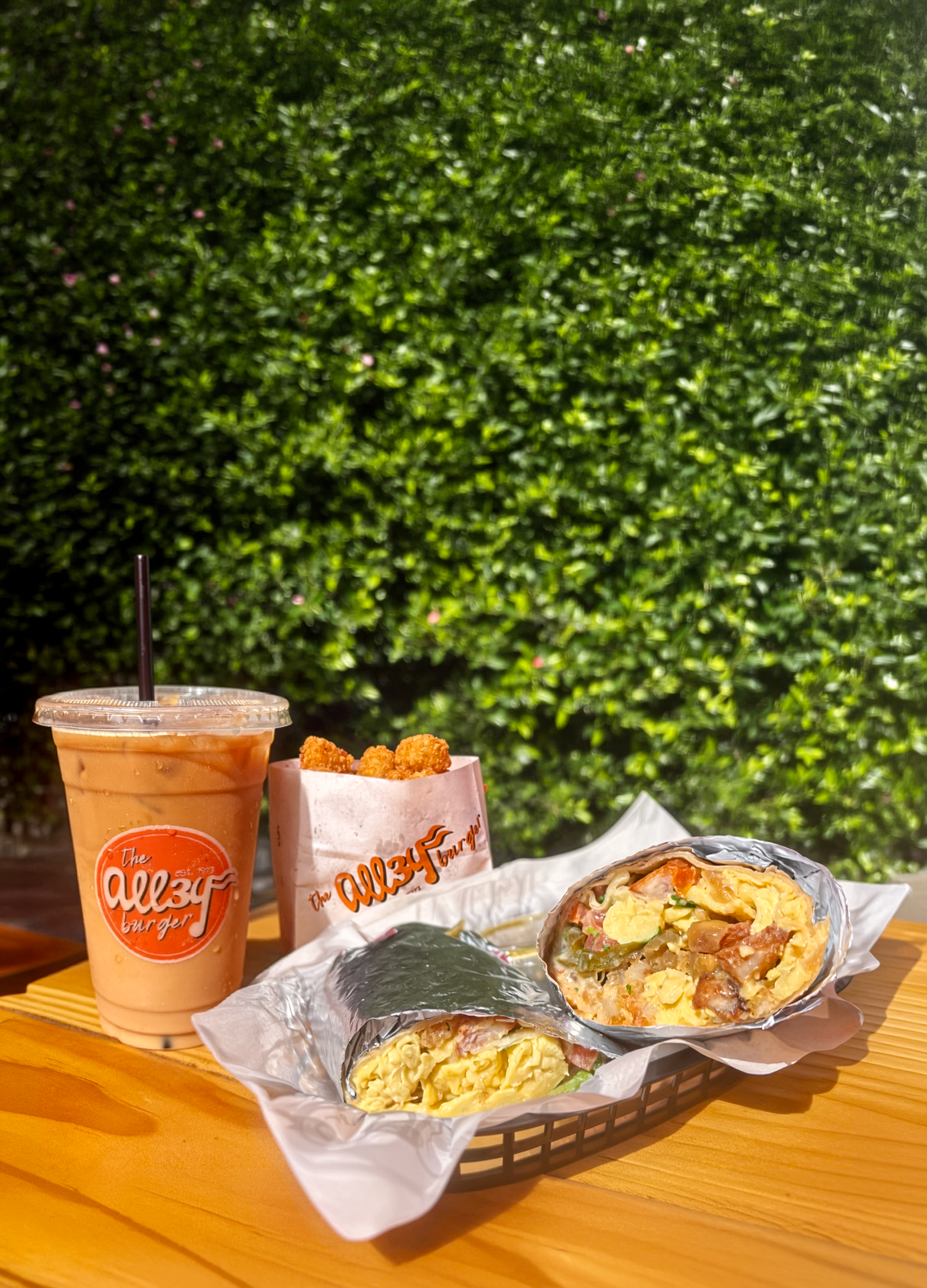Brunch burrito with iced coffee and tallow tater tots in a branded bag