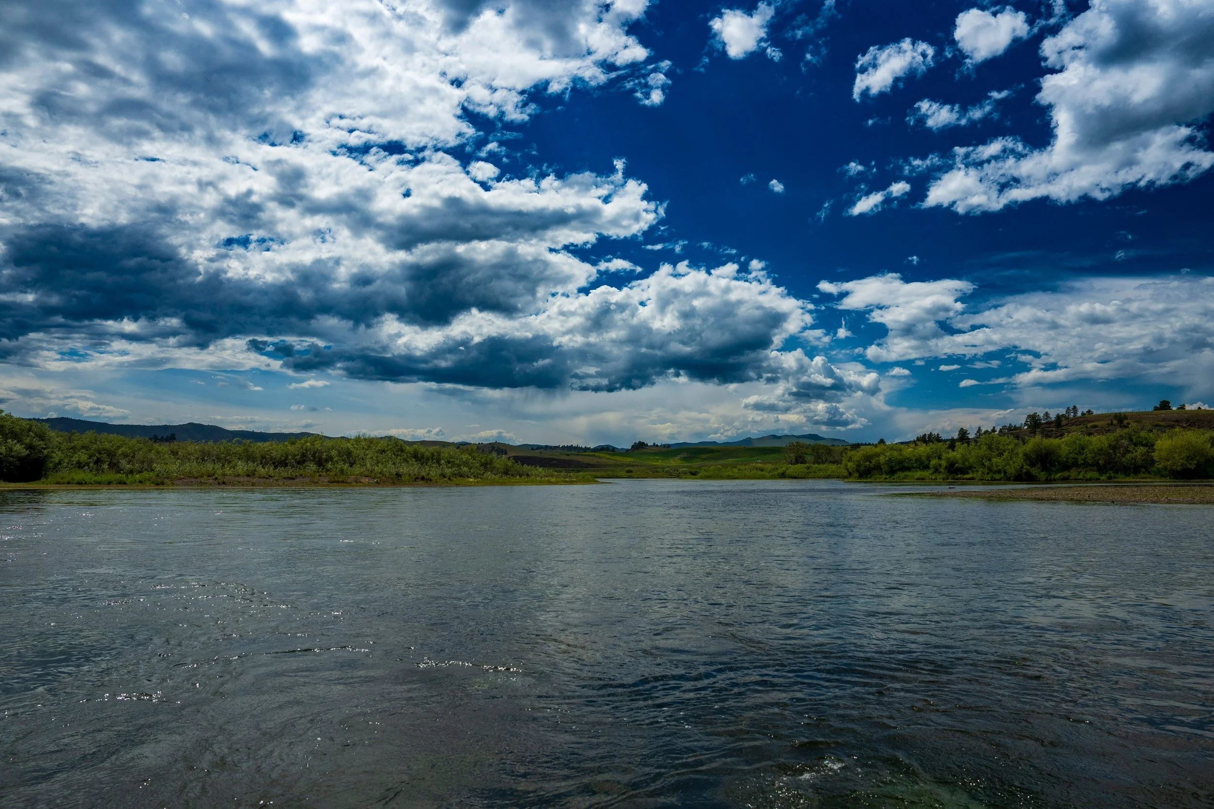 Cumulus clouds over a broad river, Montana