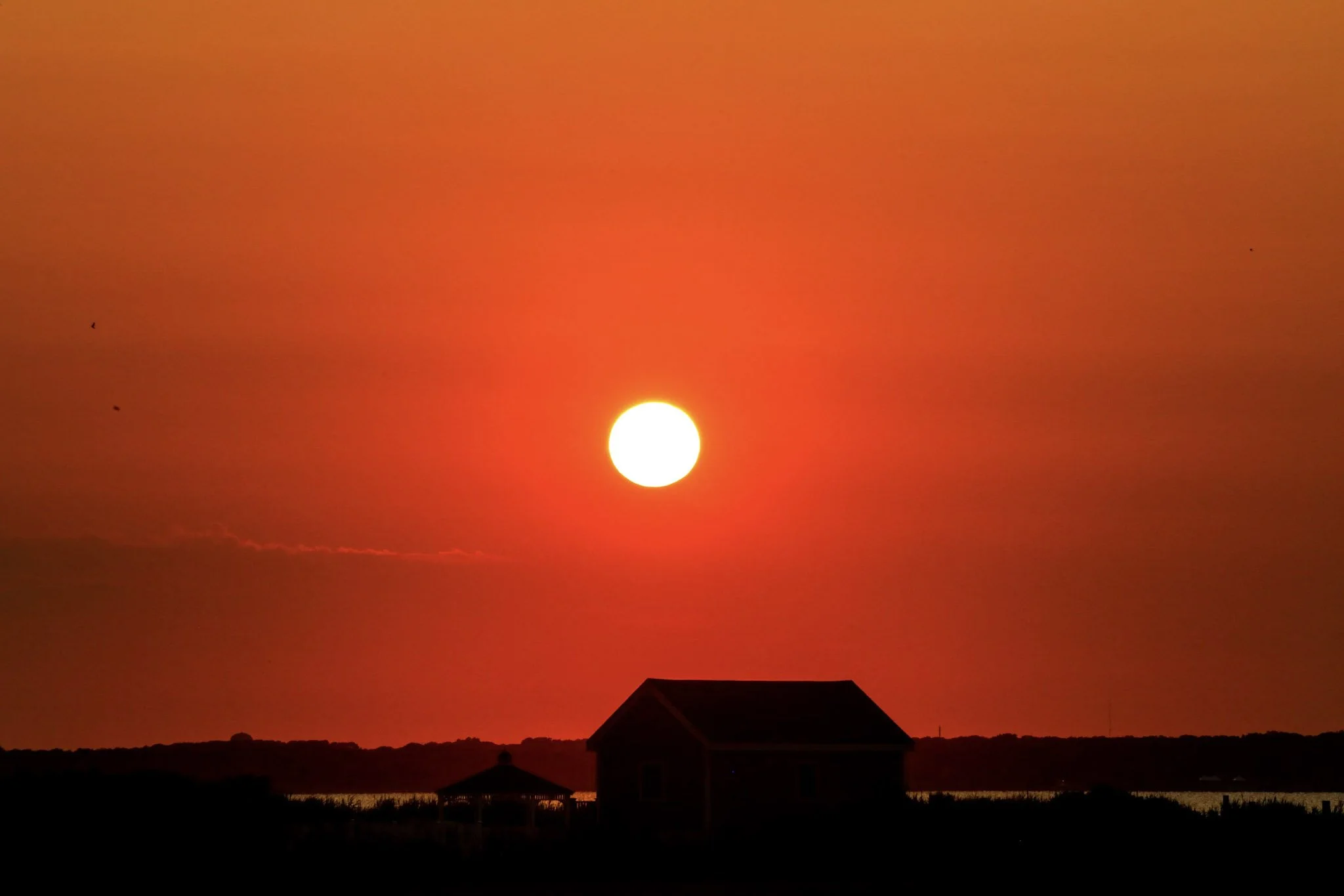 Red sun setting behind a building
