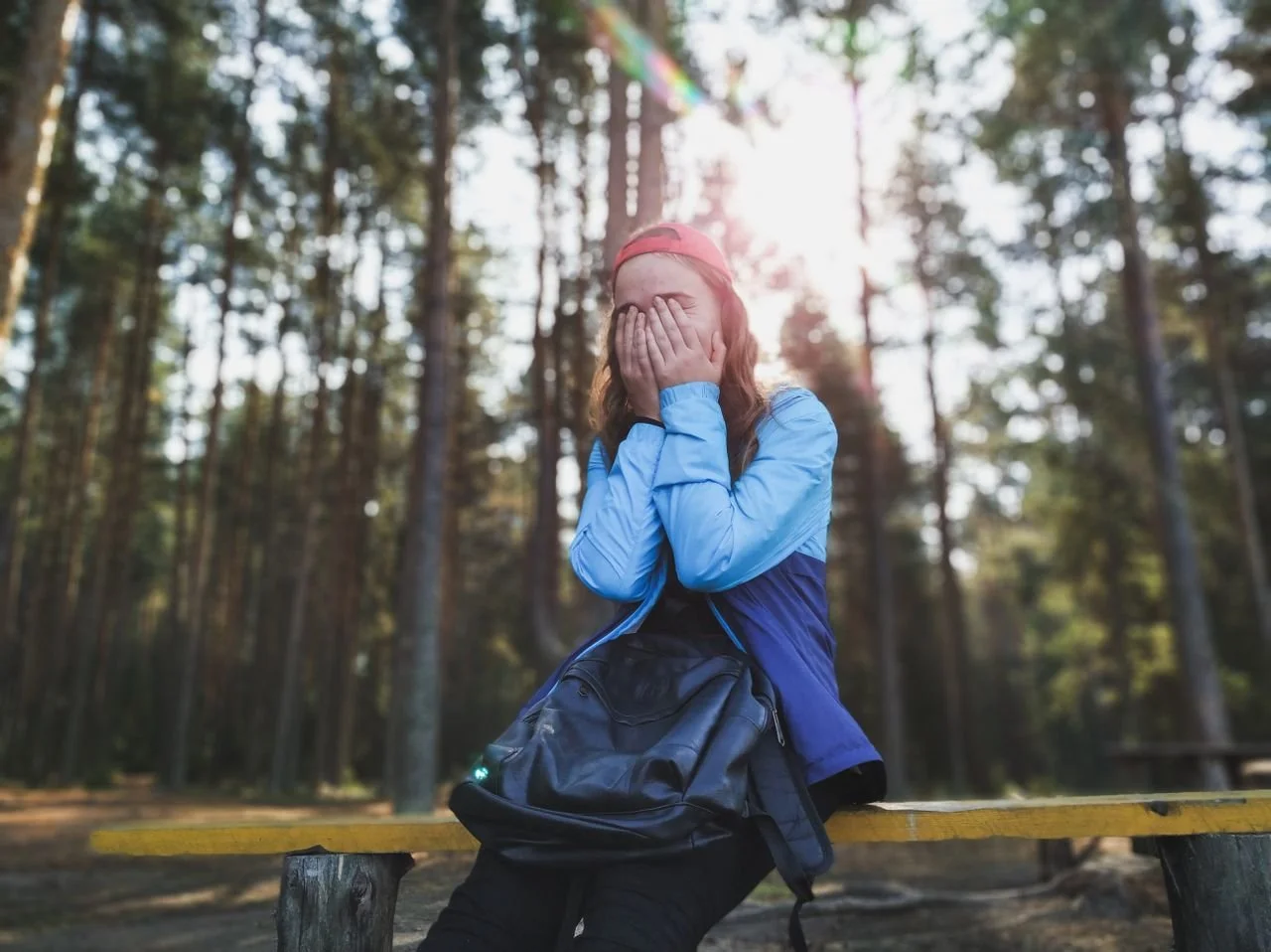 Woman sitting hiding her face with trees in background
