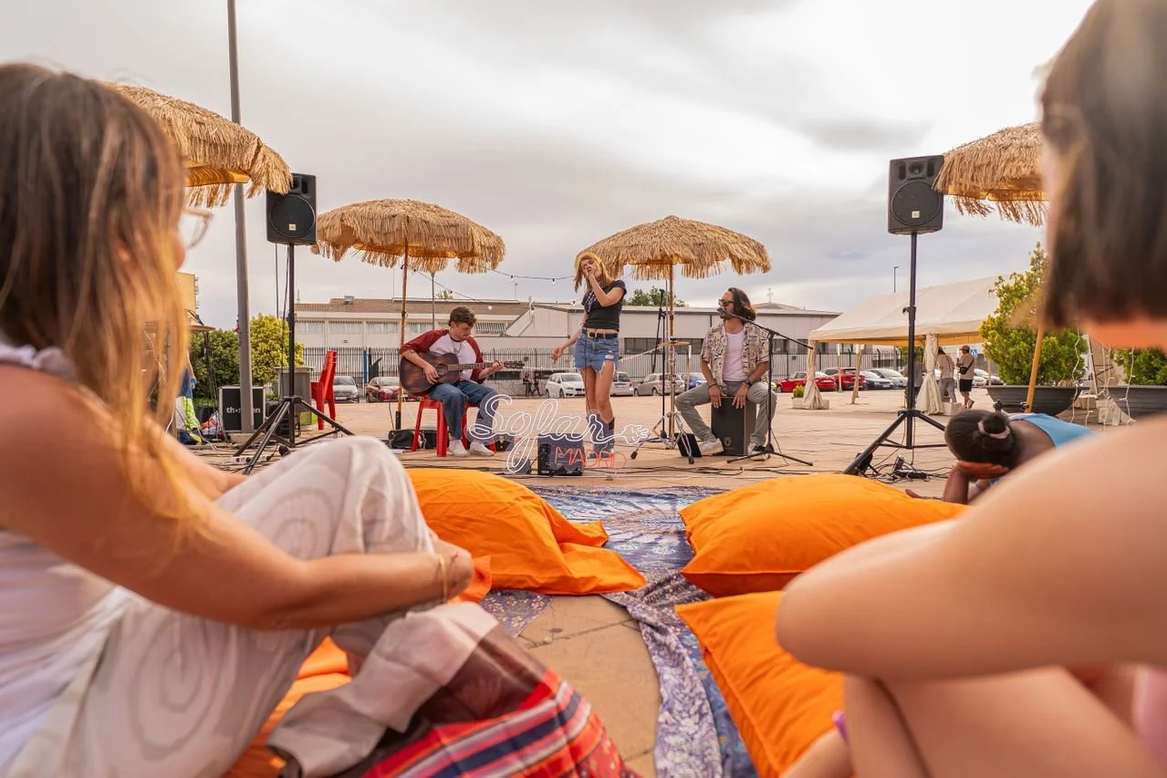 women sitting on blankets and watching a woman sing