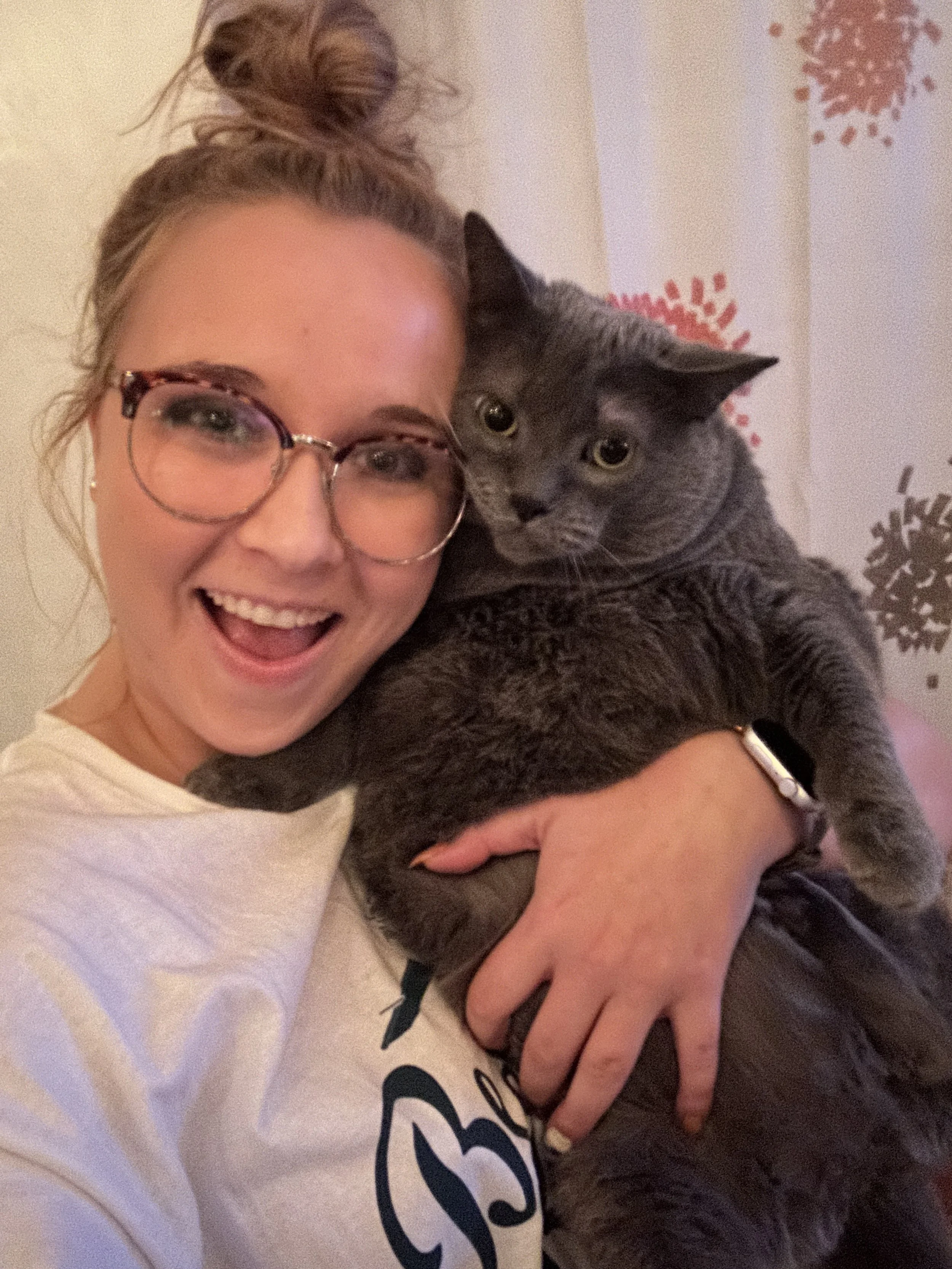 Moriah, owner of JayBird Weddings and Events smiles holding her gray cat Smokey