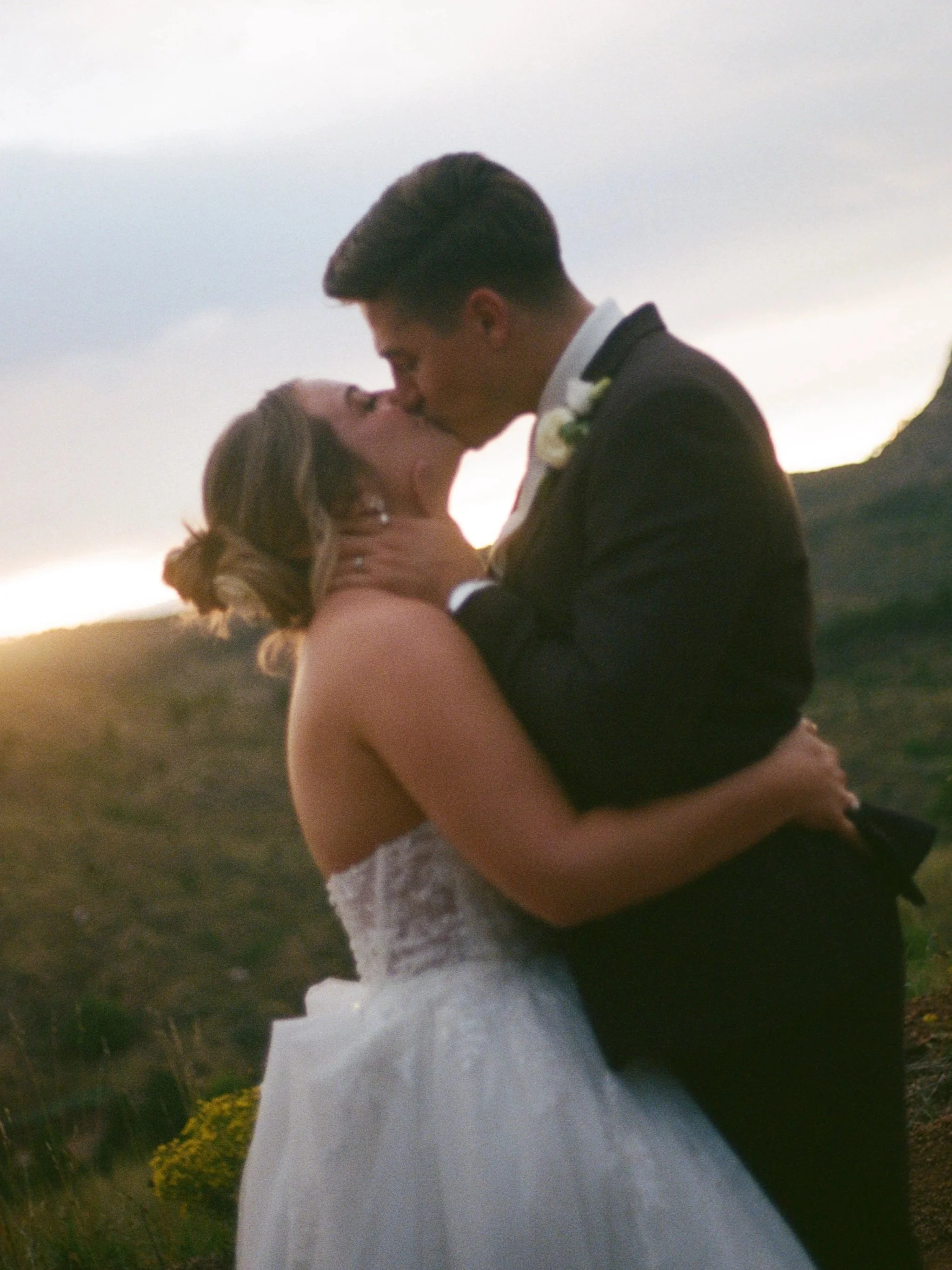 A bride and groom kiss at sunset at their wedding at Pikes Peak Ranch, planned by JayBird Weddings and Events