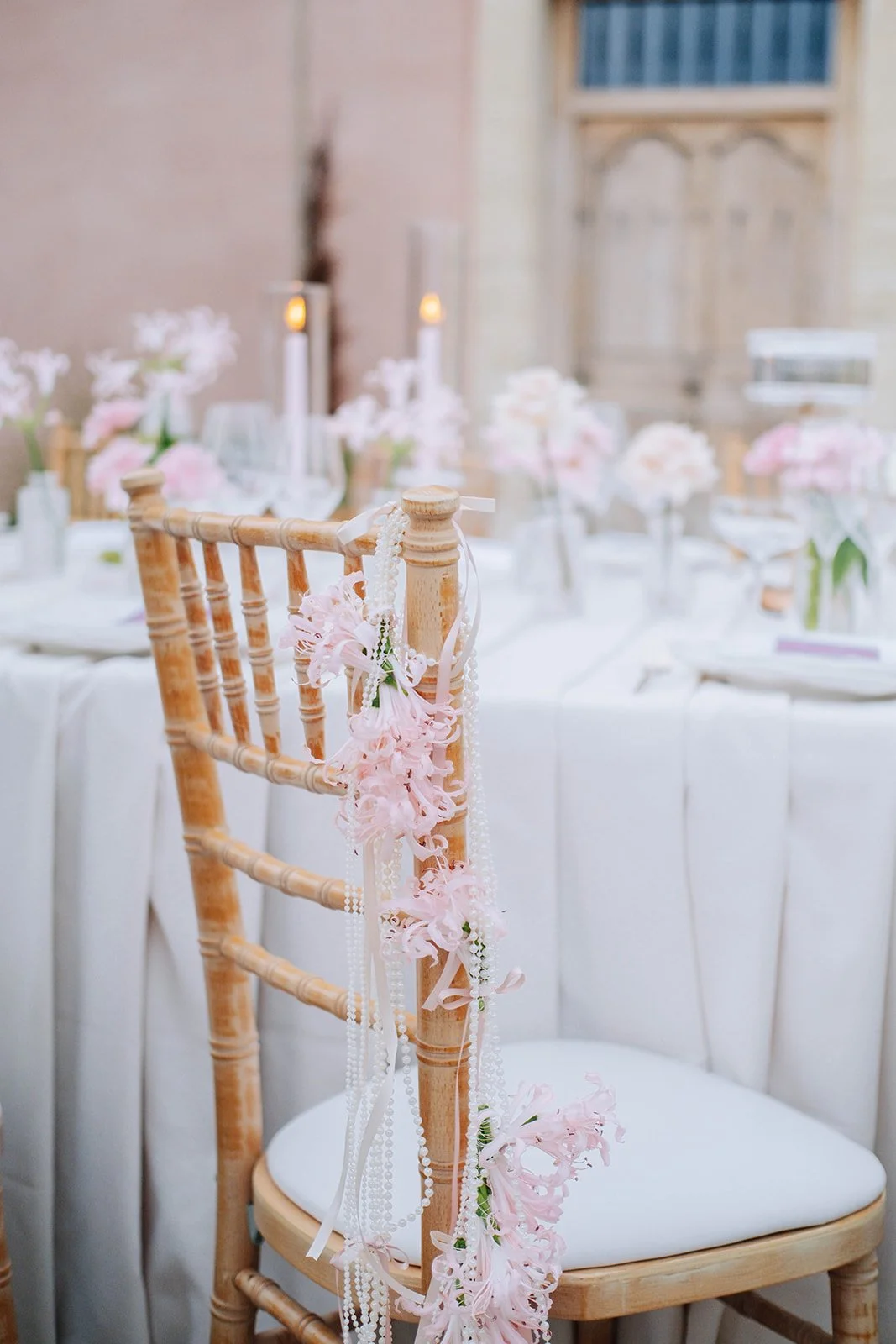 Chaise en bois décorée avec des fleurs roses et des perles, dans une salle de mariage élégante.