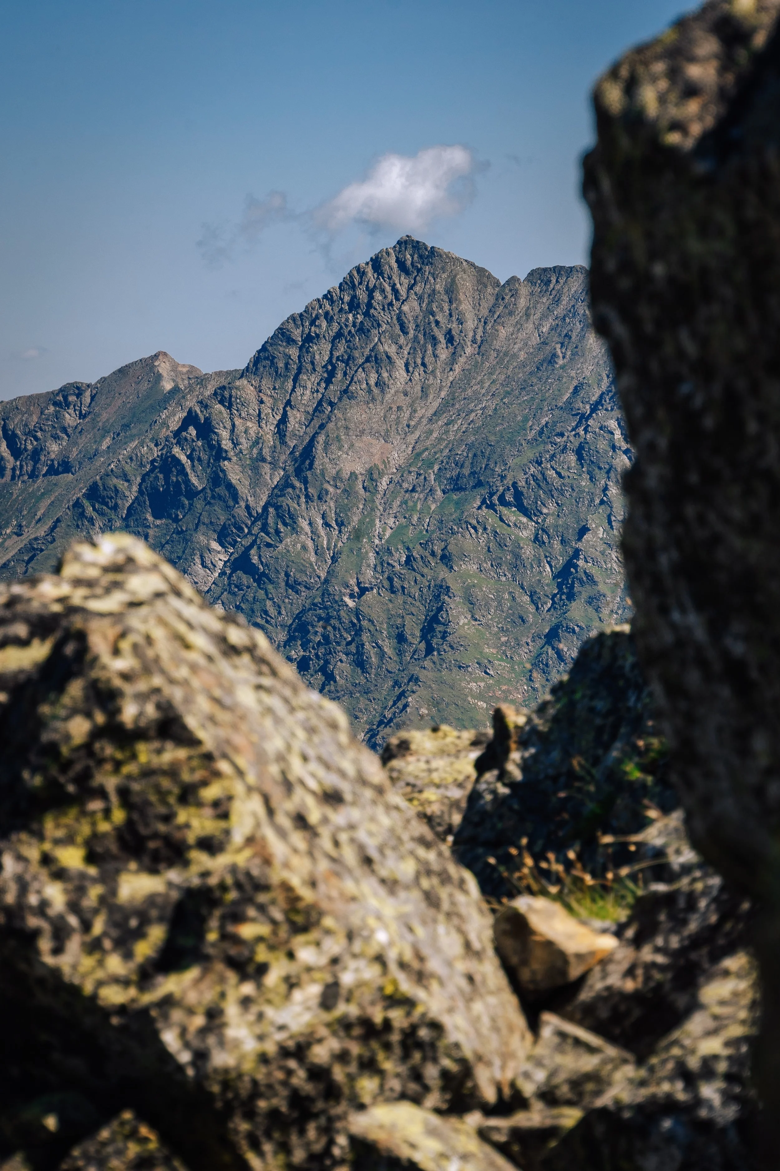 Blick auf eine Bergkette durch Felsen im Vordergrund.