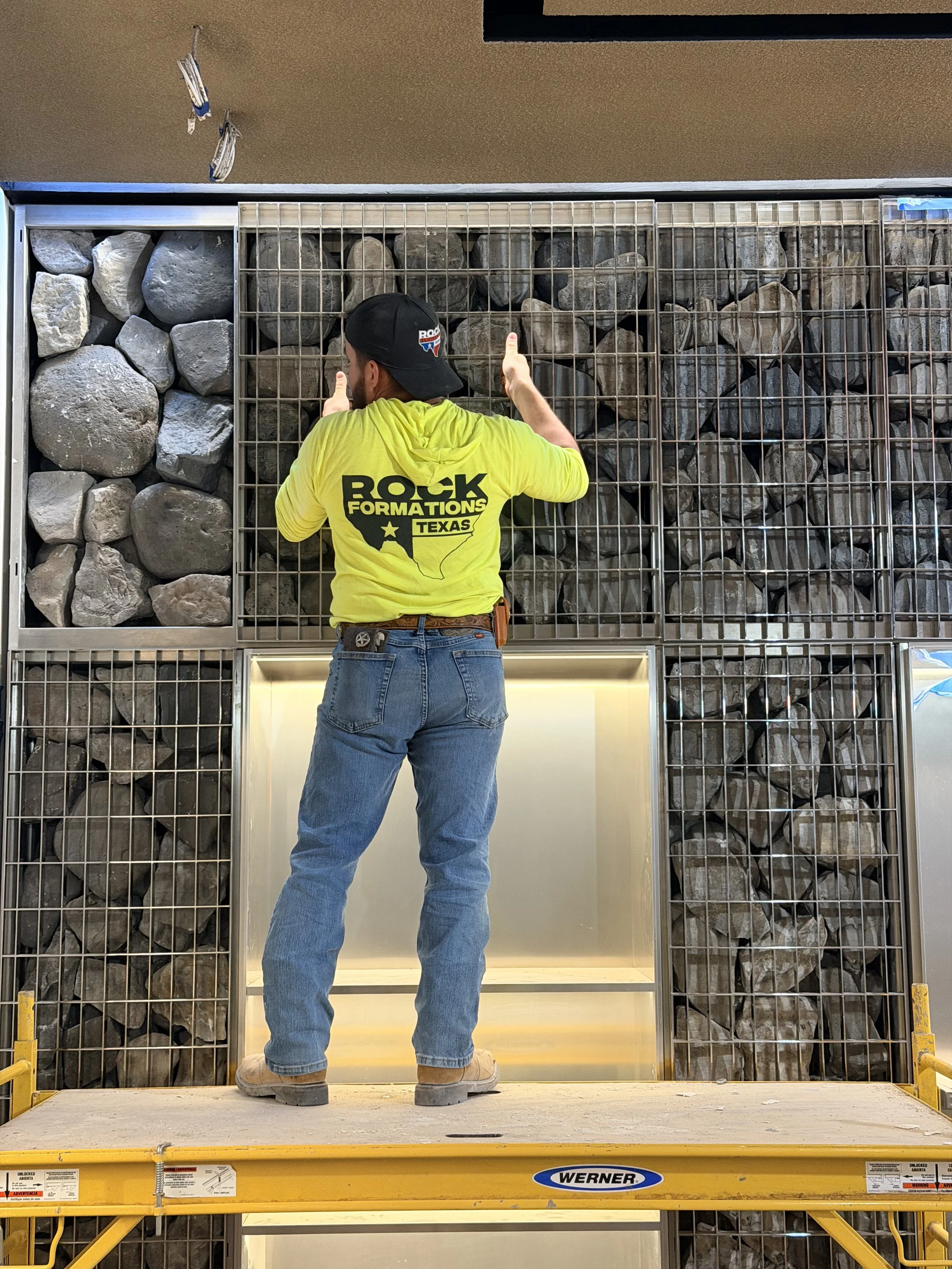 Gabion wall of artificial rock in retail space being installed