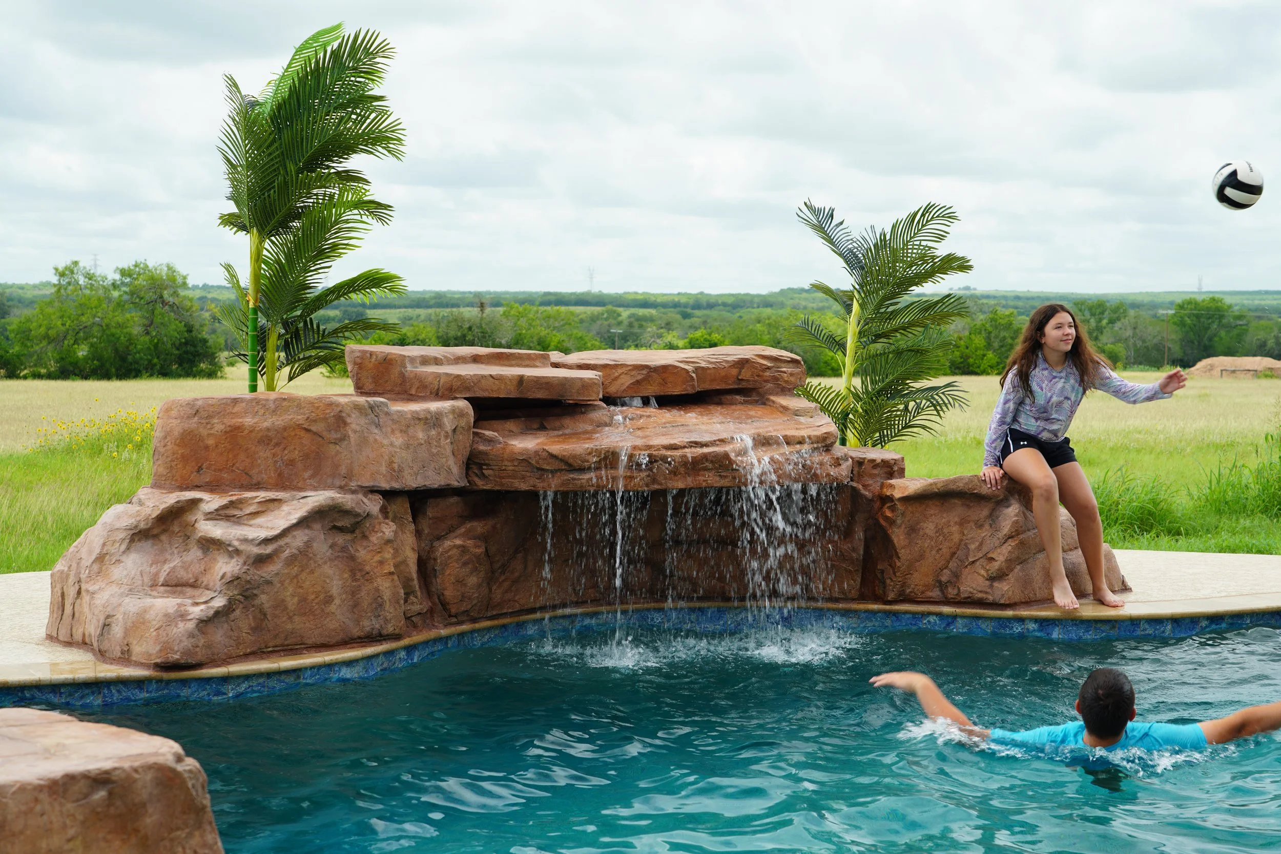 Artificial rock waterfall installed on a pre-existing pool being enjoyed by a Texas family.