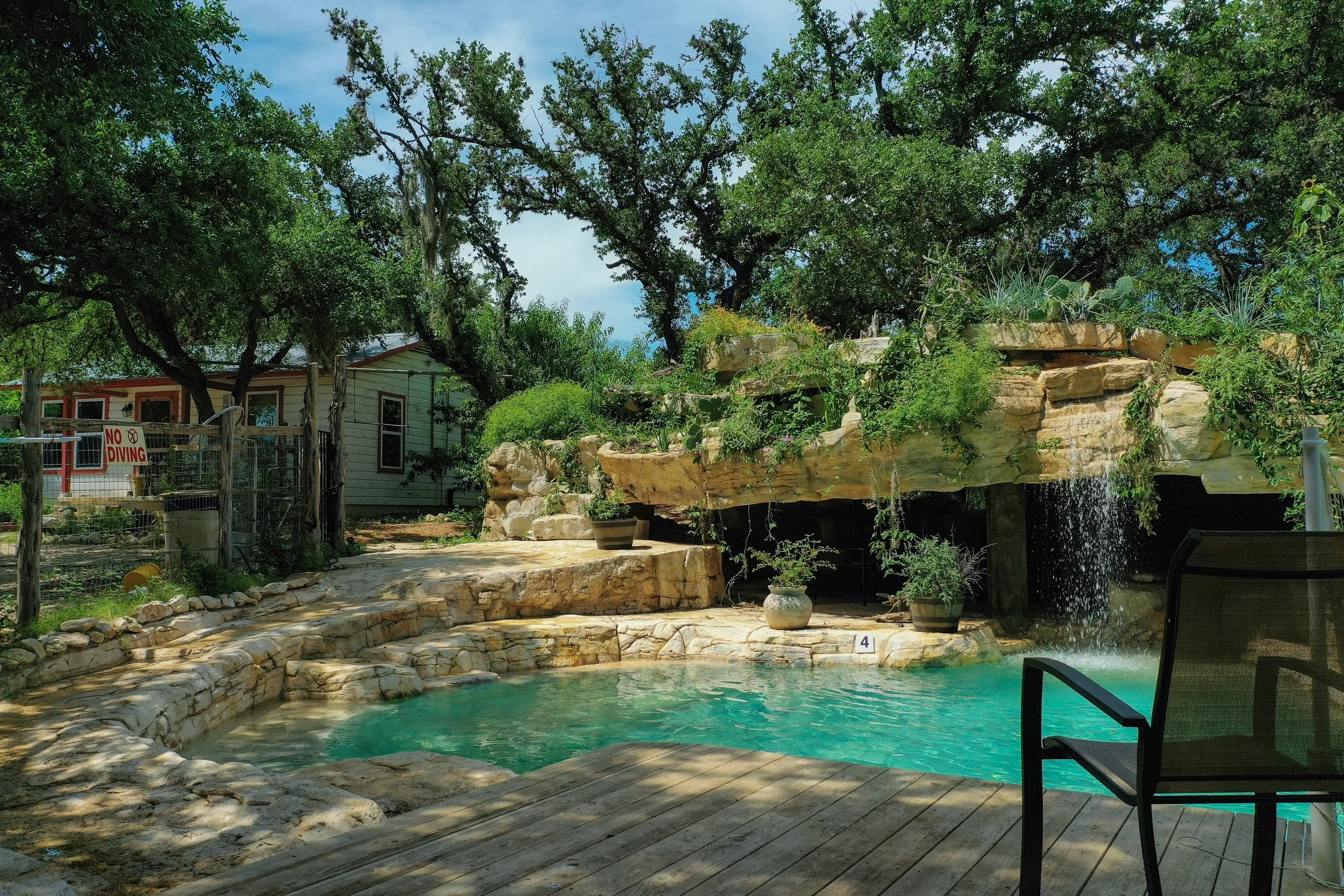 Custom artificial lagoon pool in a backyard with a pool waterfall trickling into a crystal blue pool surrounded by native plants
