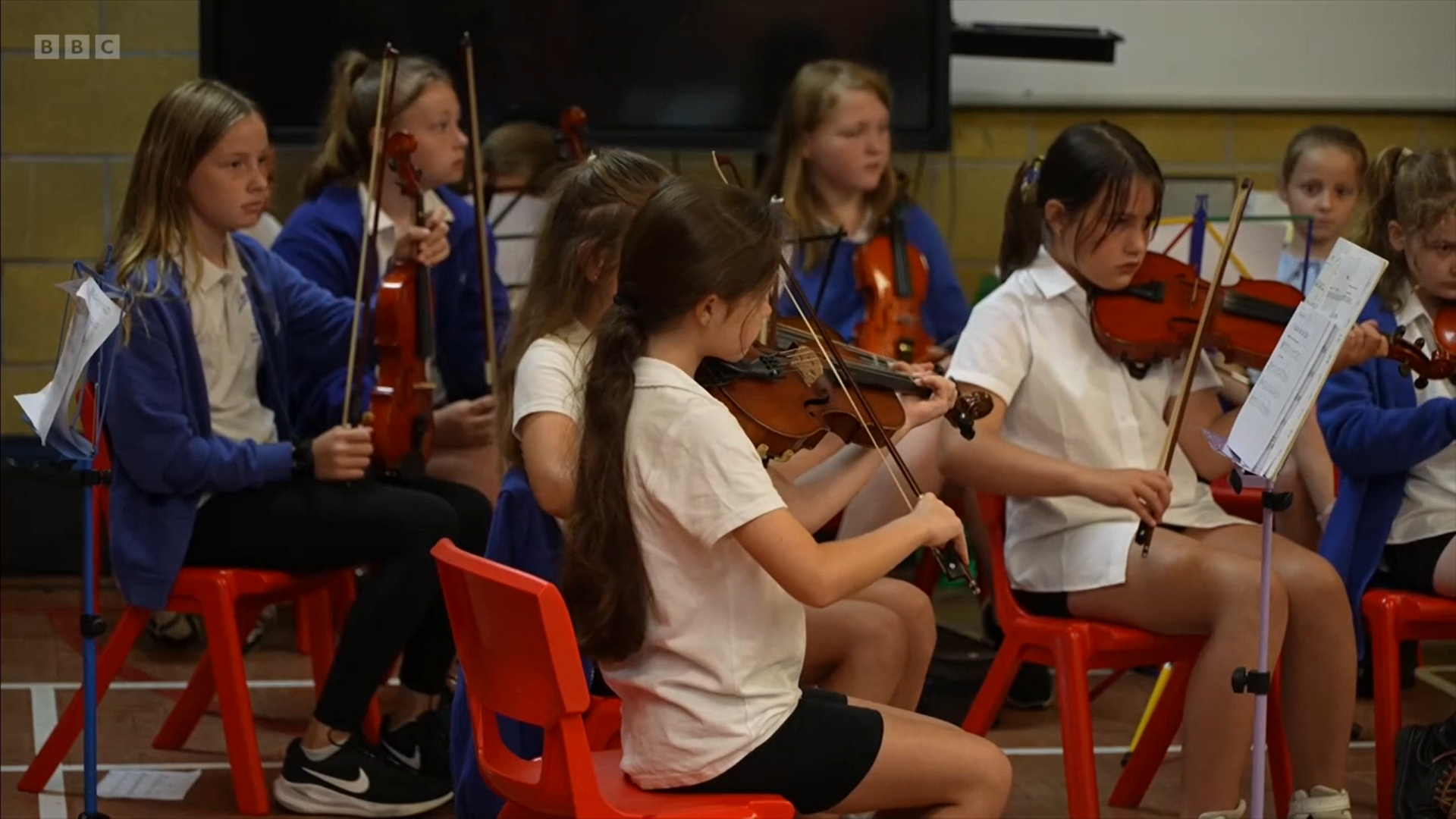 Young children playing violins during a music class or concert.