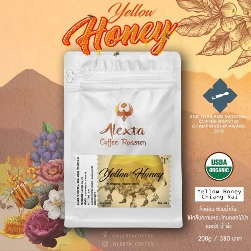 A bag of Alexza Yellow Honey coffee roasted, featuring a label with yellow honey bees and honeycomb illustrations. The packaging also displays awards and organic certification, with background illustrations of flowers, grapes, and honey.
