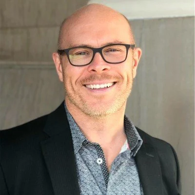 Man wearing glasses and a suit, smiling