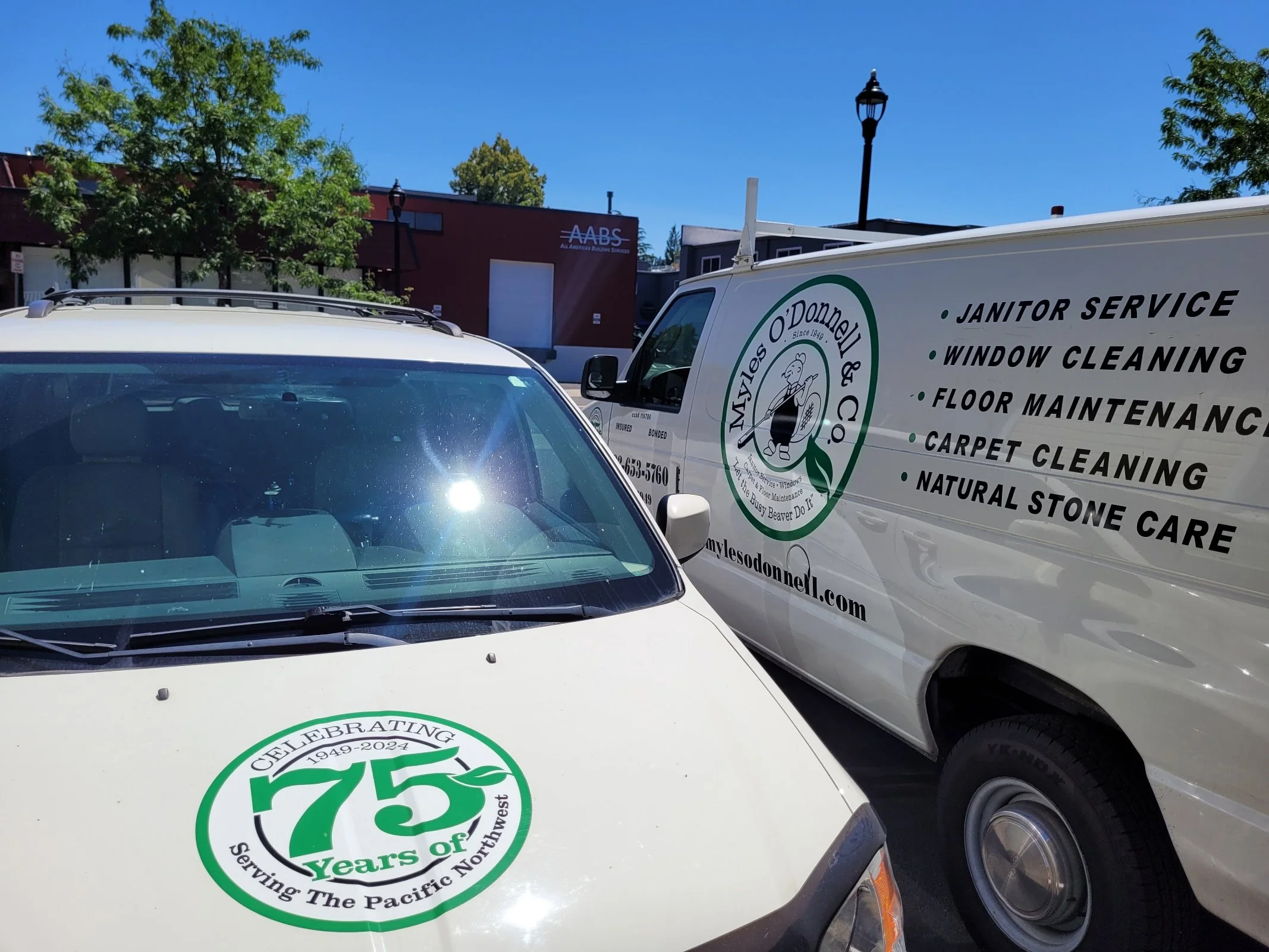 Two Myles O'Donnell company vans parked side by side on a sunny day