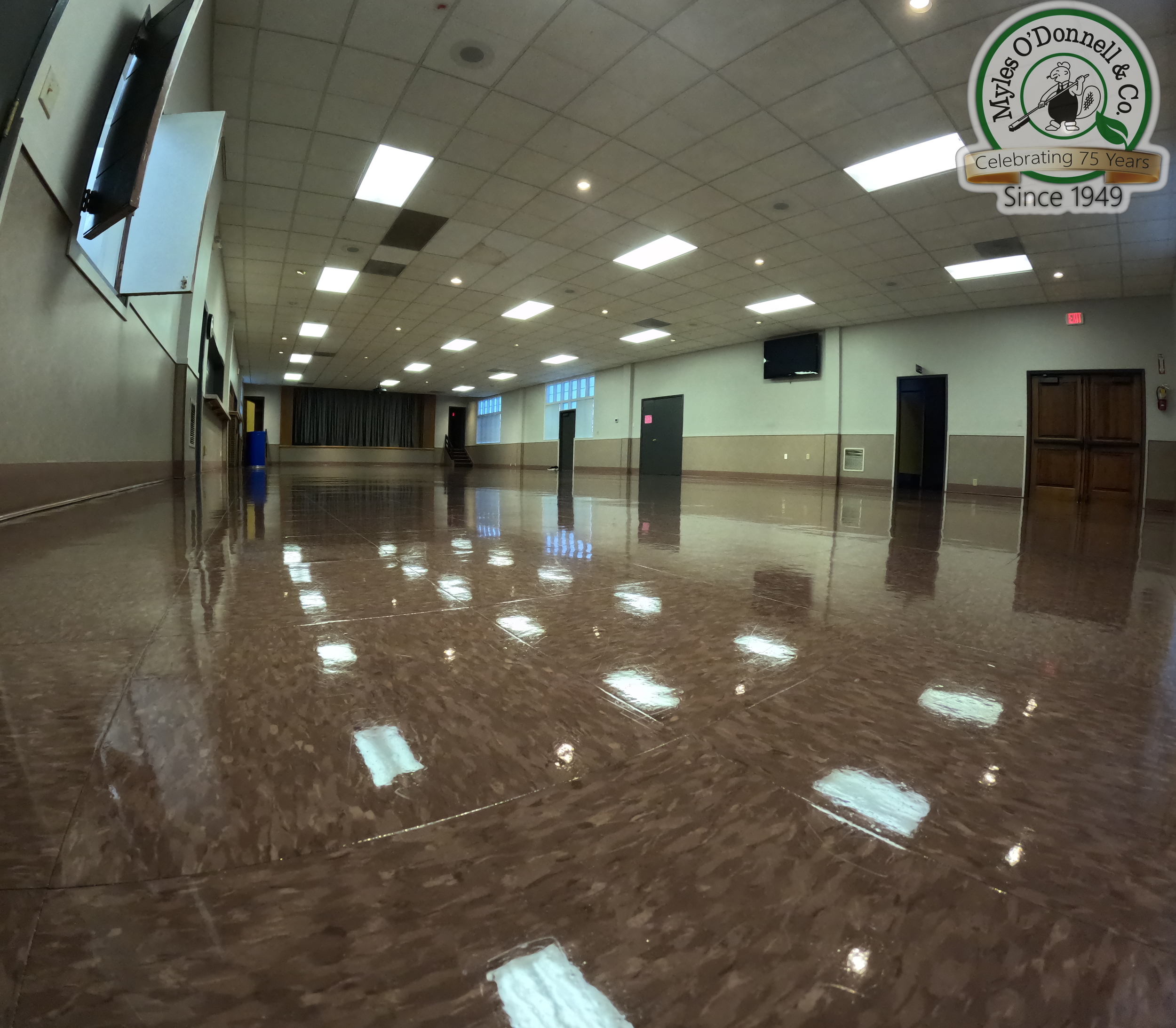 A wide angle shot of a shiny polished VCT floor in a large empty event space