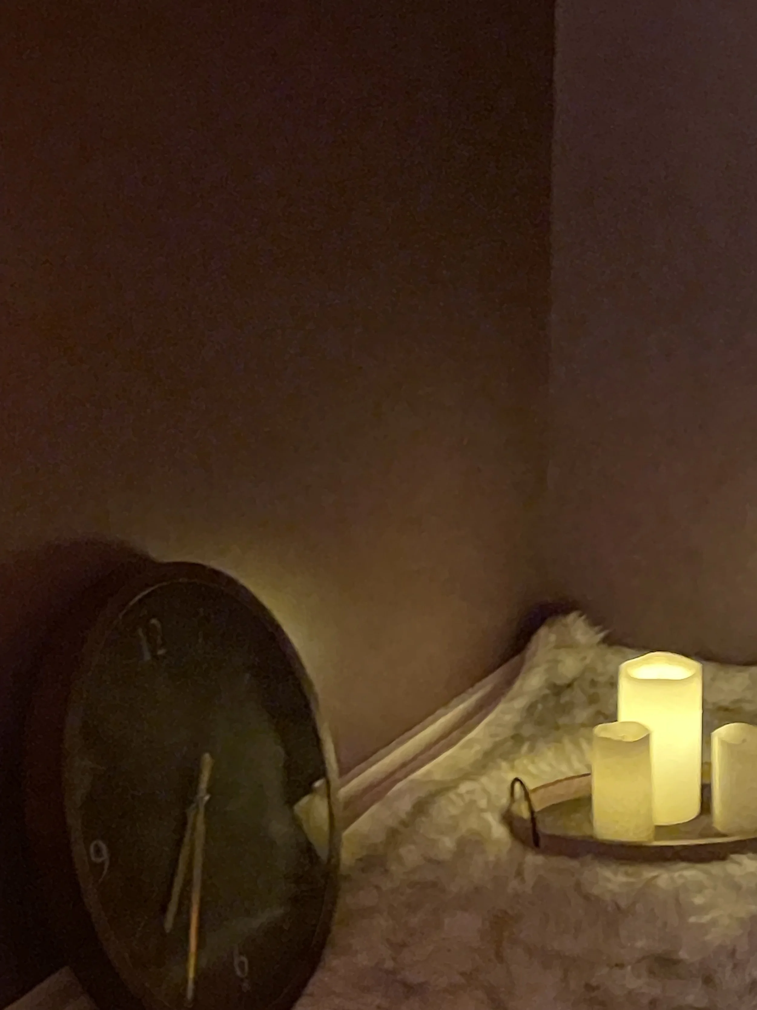 Dark room with candles and clock on the ground.