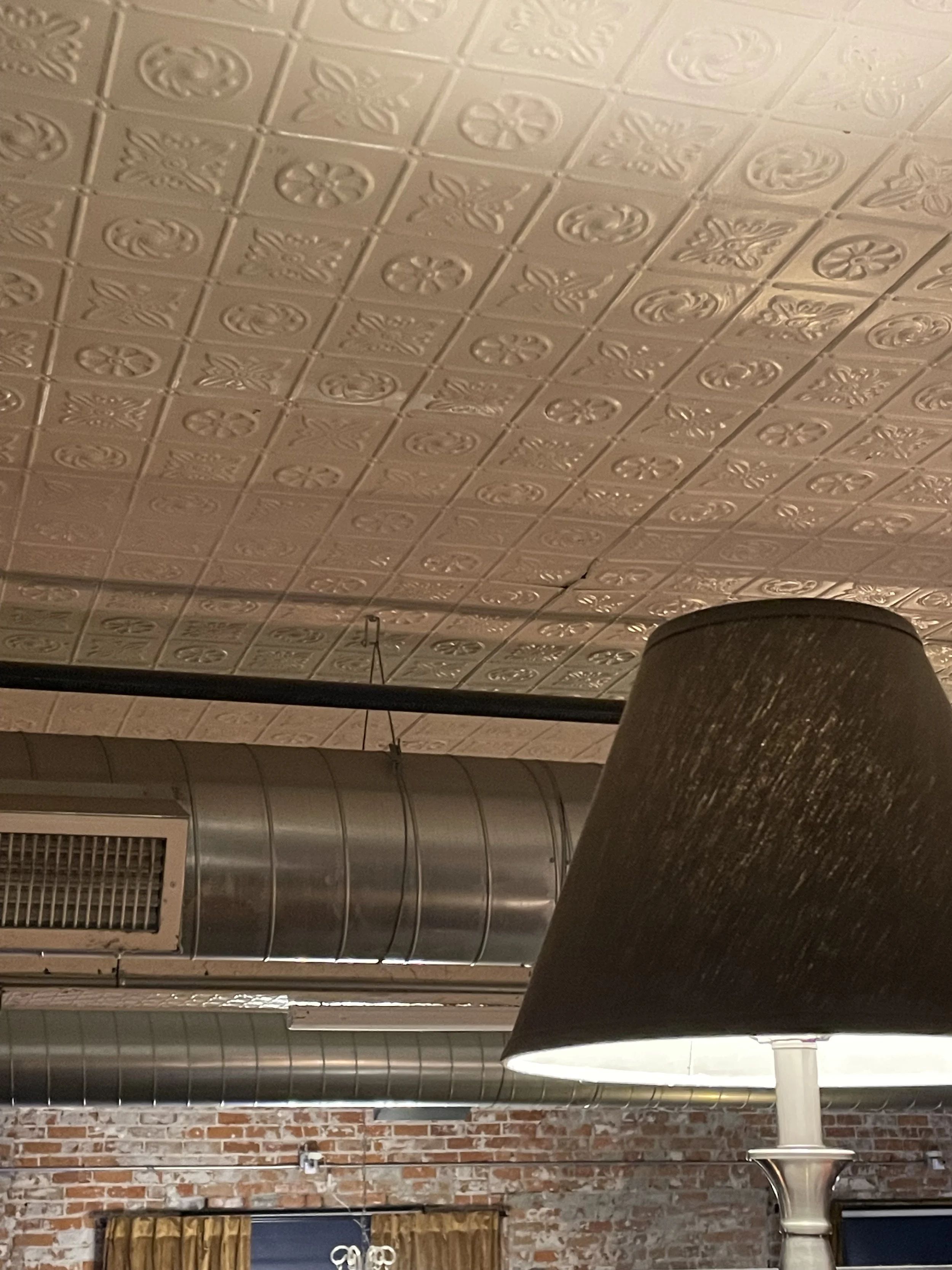 Picture of a brick room near the tile ceiling with a lamp in the right side of the photo.