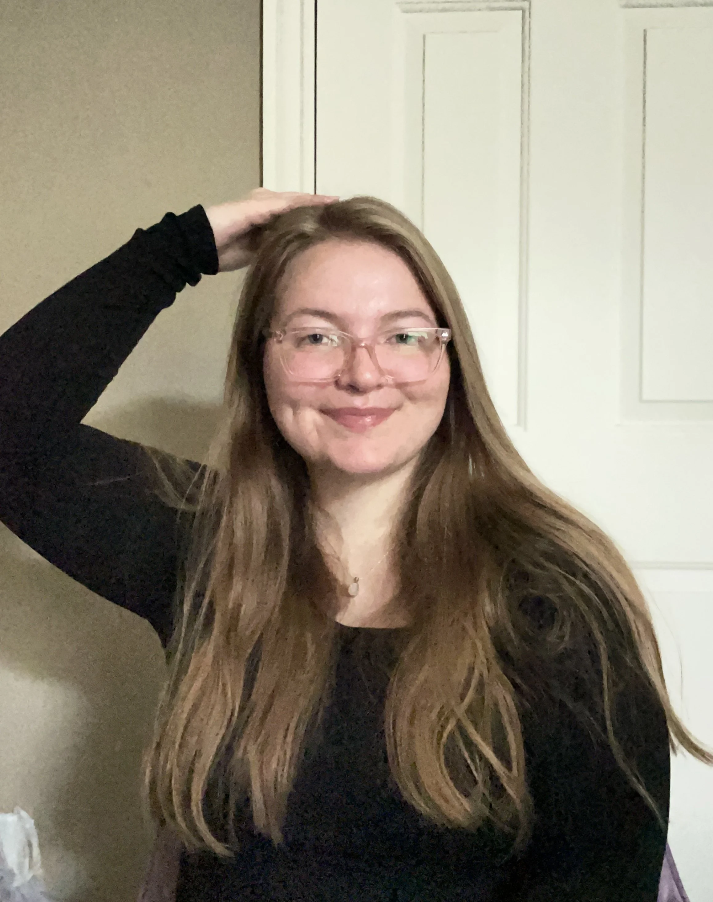 Margaret EFT Practitioner looking at the camera and smiling while holding the top of the head point.