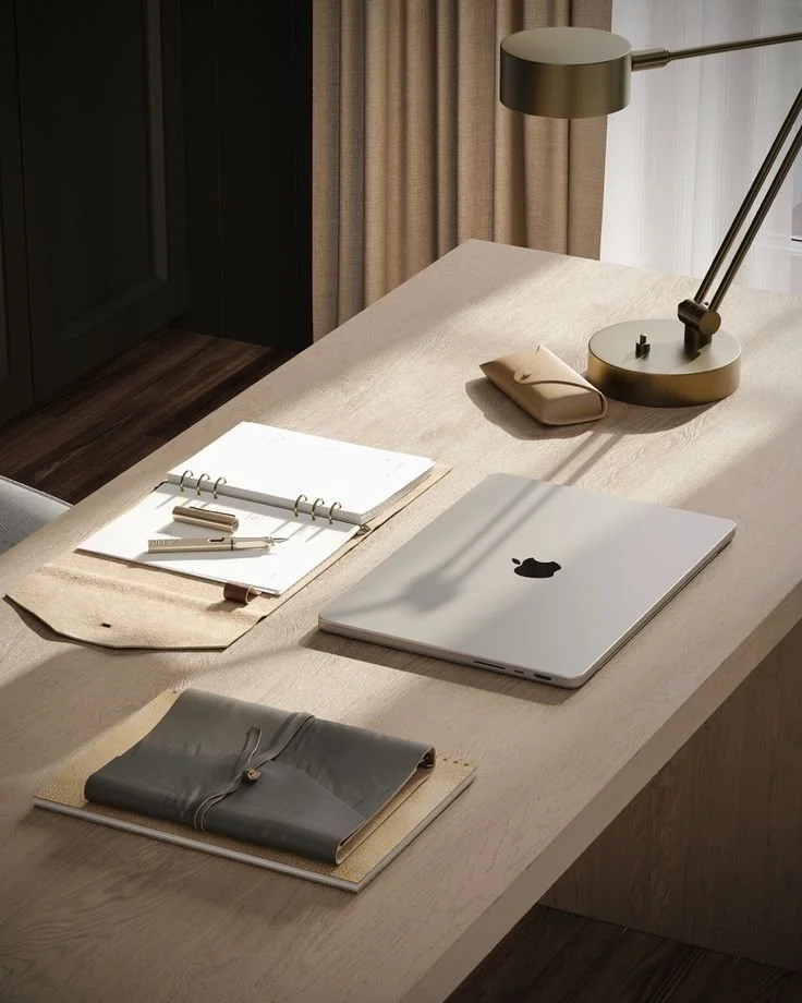 Minimalist workspace with a laptop, open notebook, pencil case, and desk lamp on a wooden table.