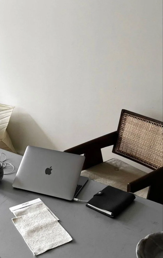 Minimalist workspace with a laptop, notebook, and chair.