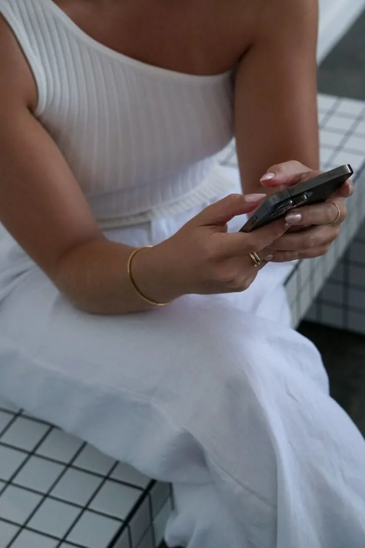 Person in white outfit holding a smartphone