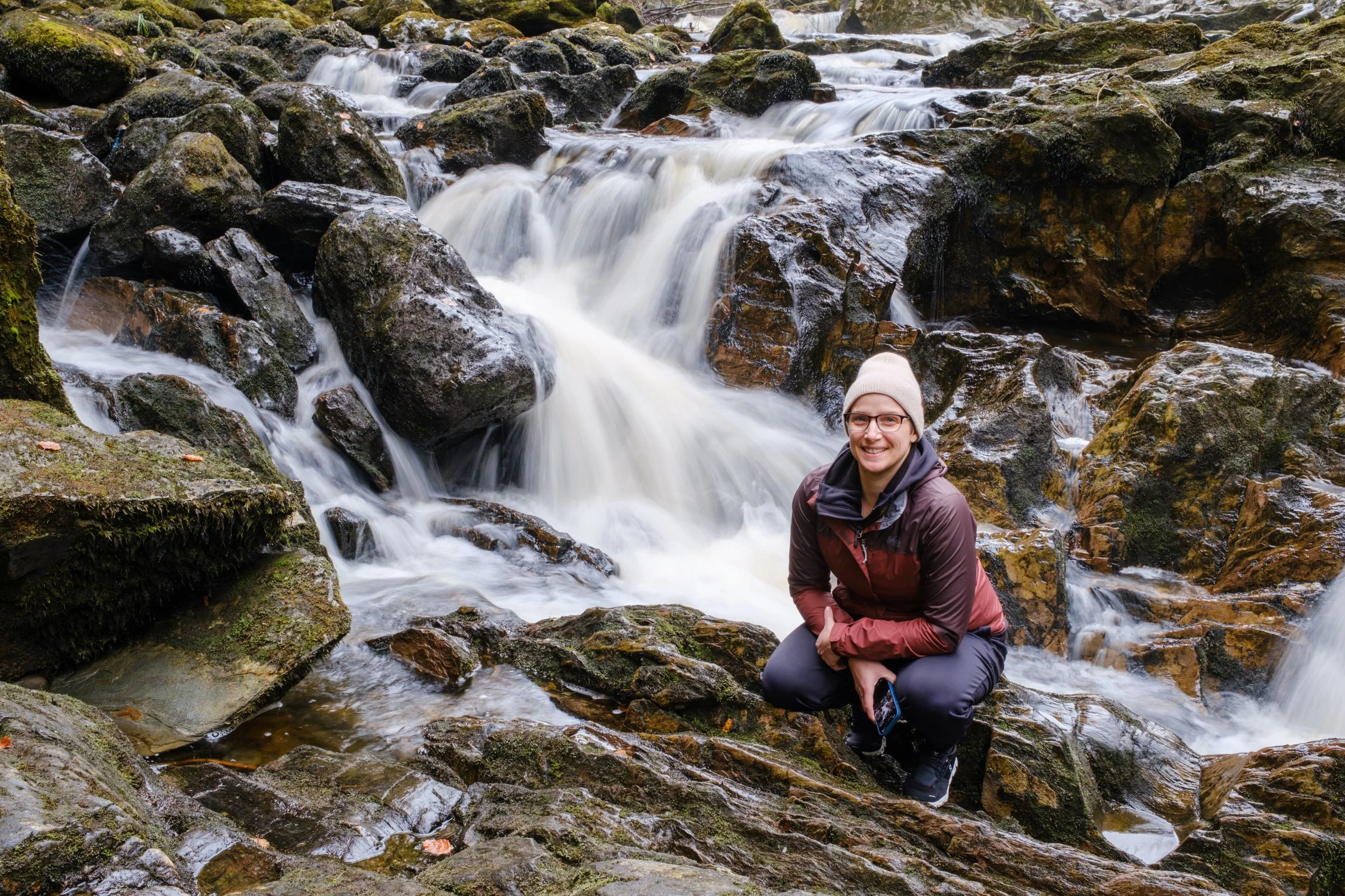 Brittany kneeling among waterfalls