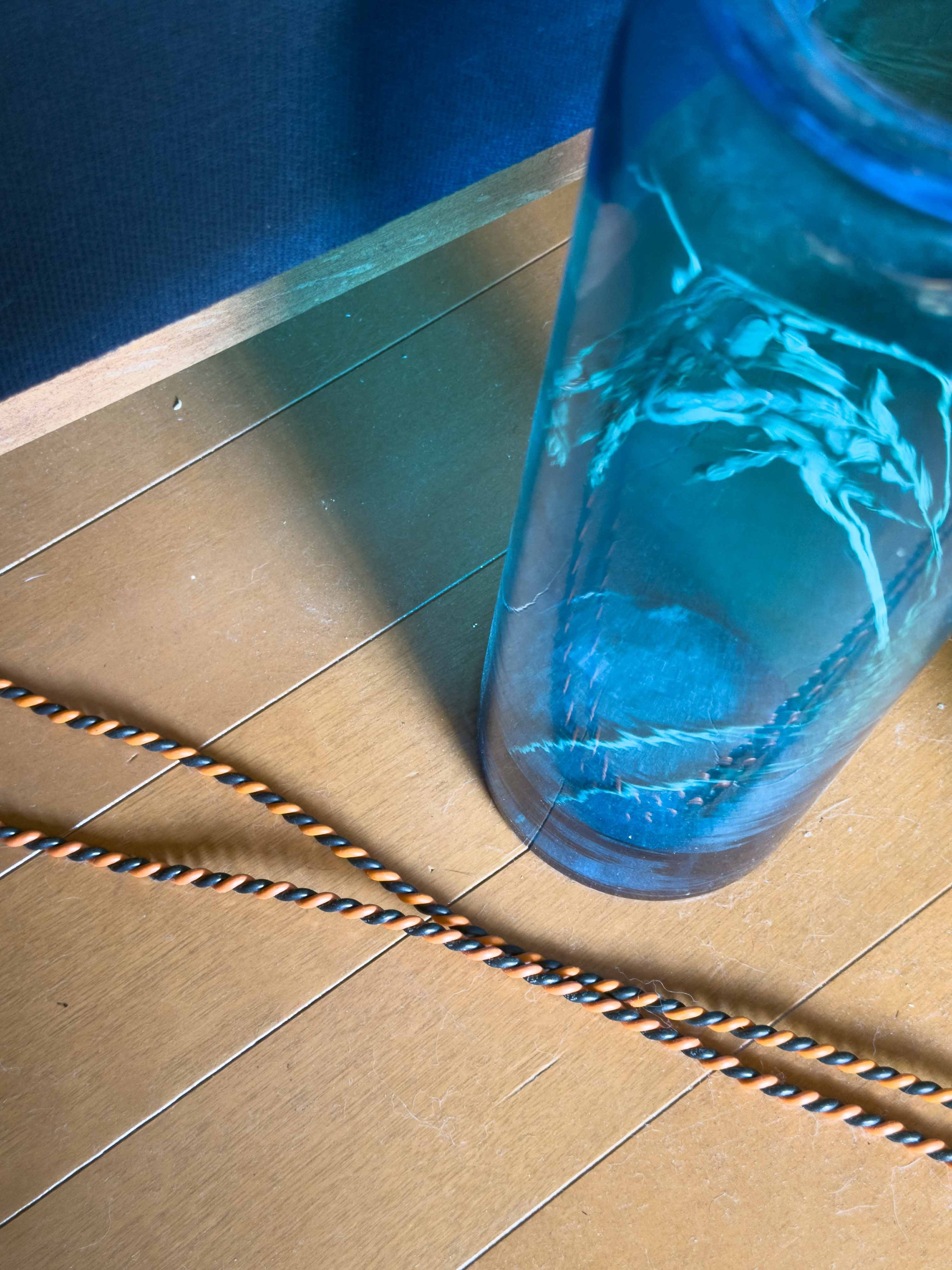 木製の床の上にガラスの花瓶と絡まった電気コード