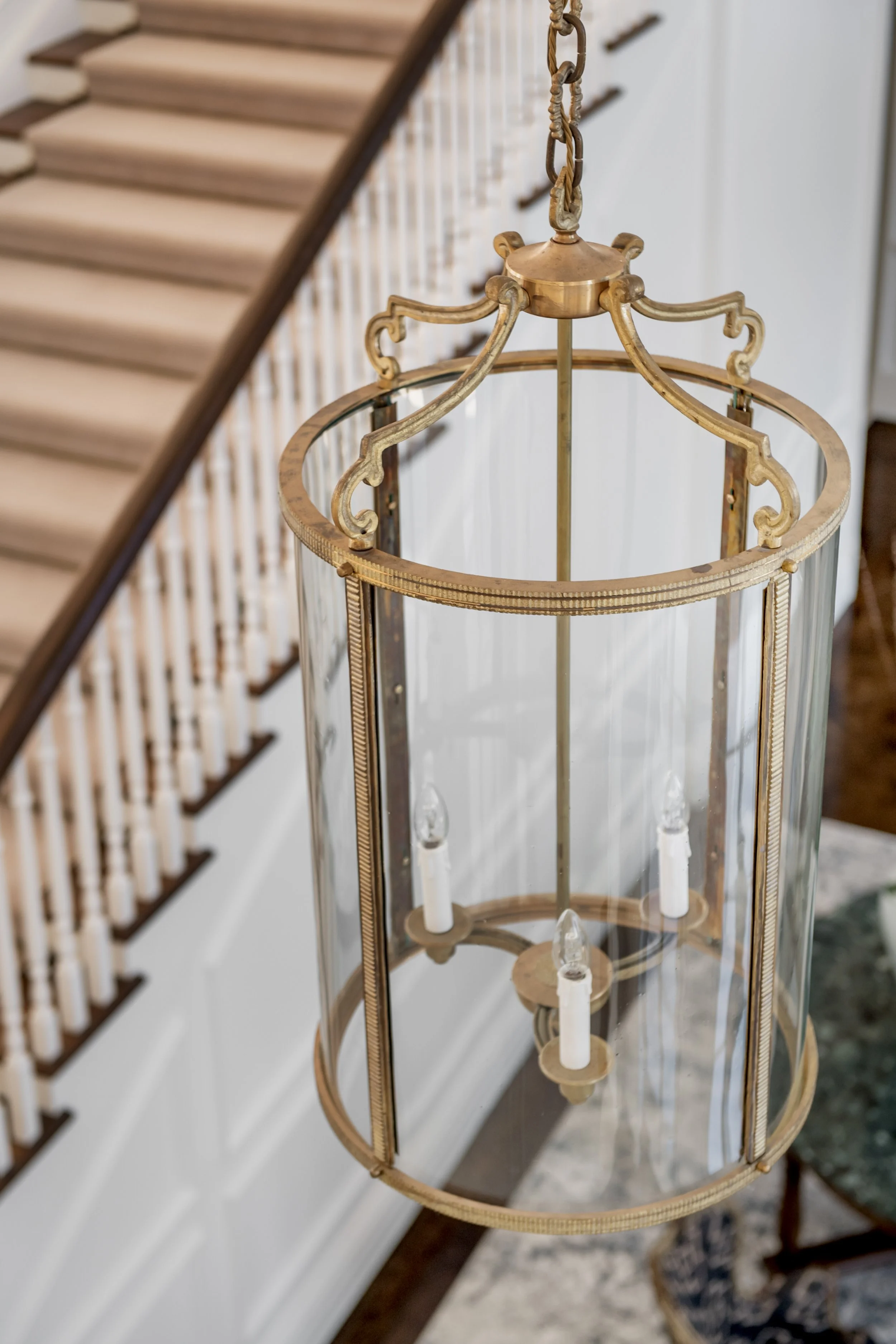 A brass and glass chandelier hanging from the ceiling inside a house.