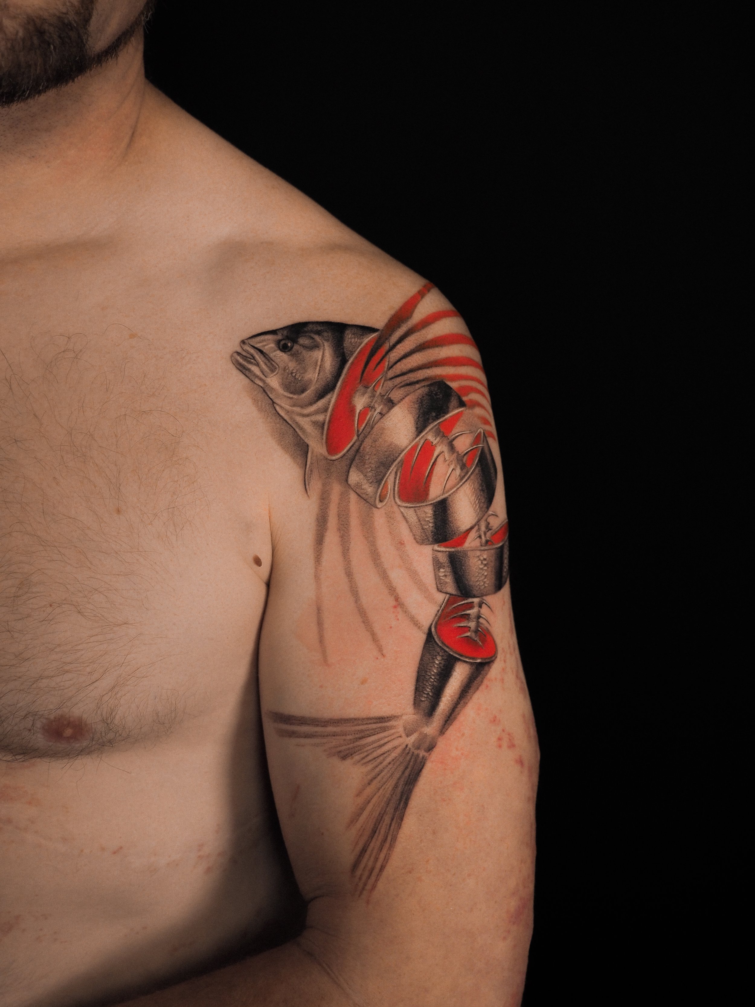 Tattoo of a stylized flower with black and red ink on a person's arm.