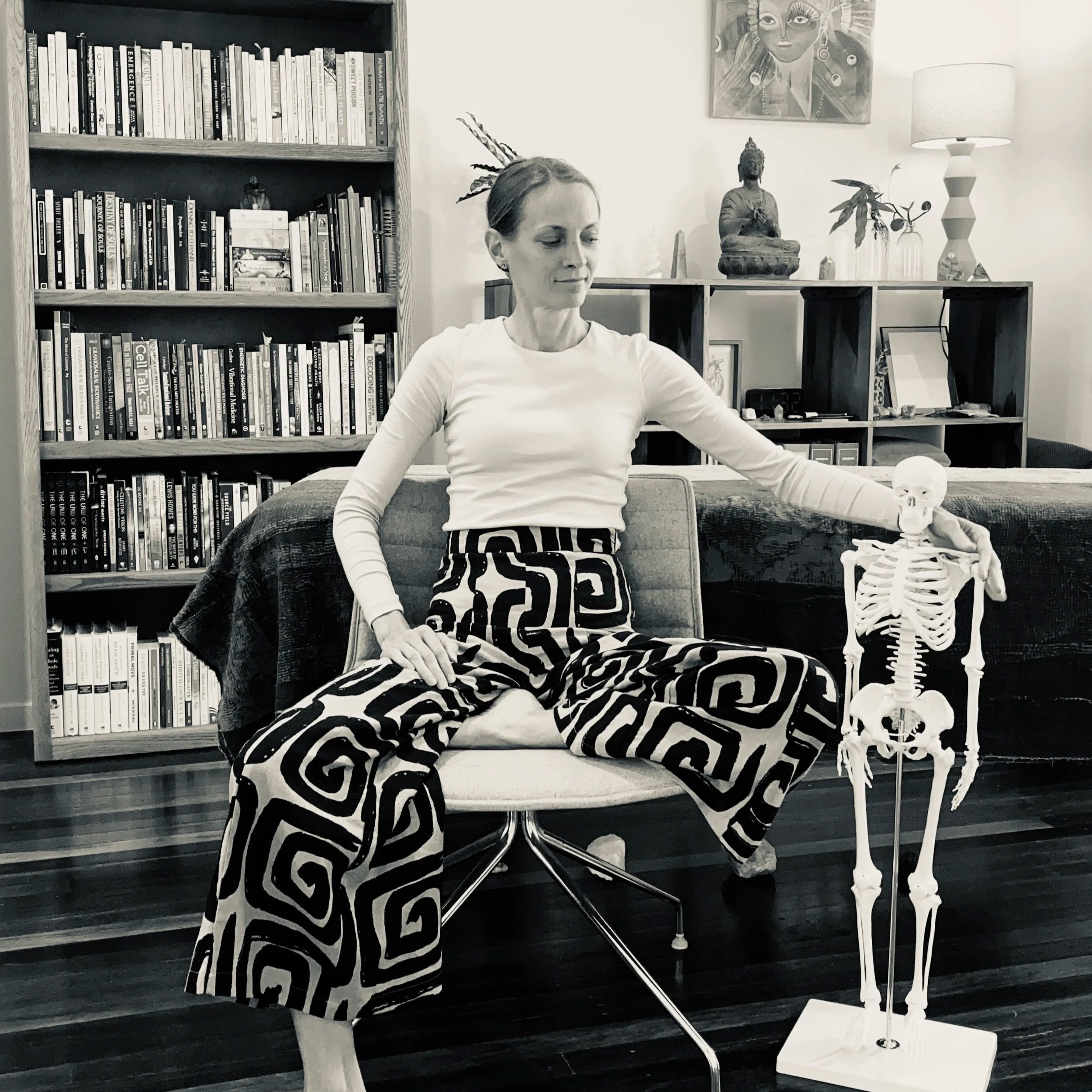 Biodynamic craniosacral, nervous system & intuitive practitioner in a treatment room viewing a model anatomy skeleton.