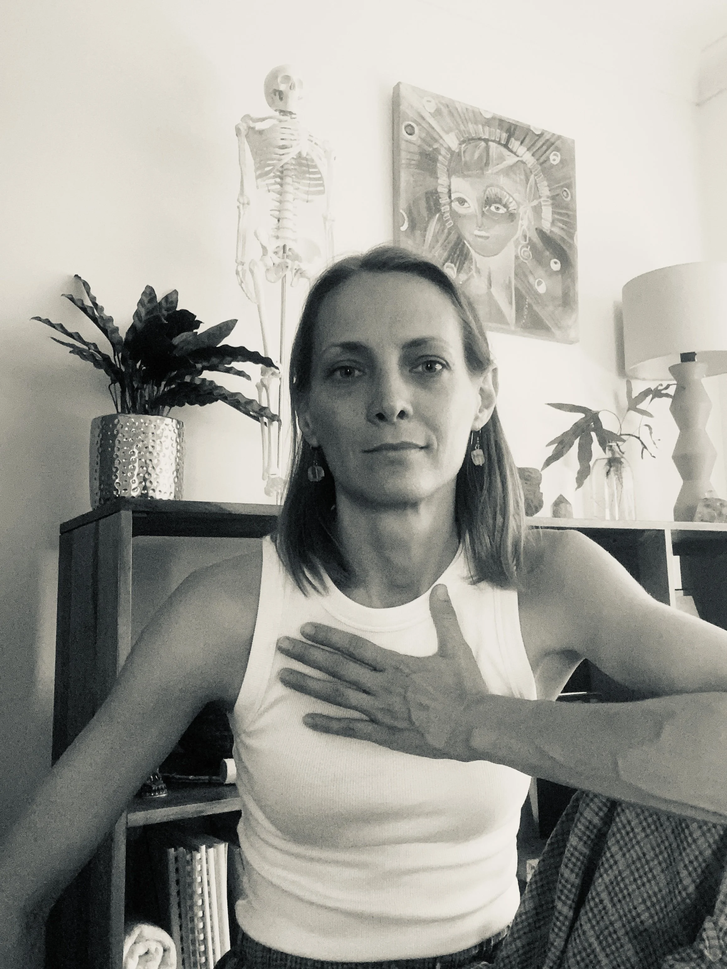Biodynamic craniosacral, nervous system & intuitive practitioner in a treatment room with her hand on her heart.
