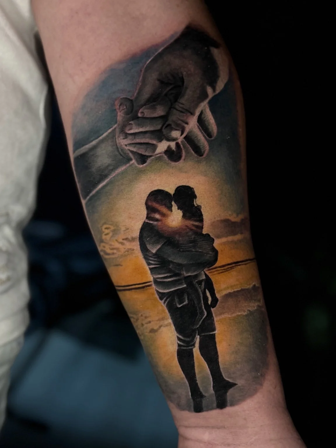 Colour realism family tattoo with a father holding his child and clasped hands, Bournemouth