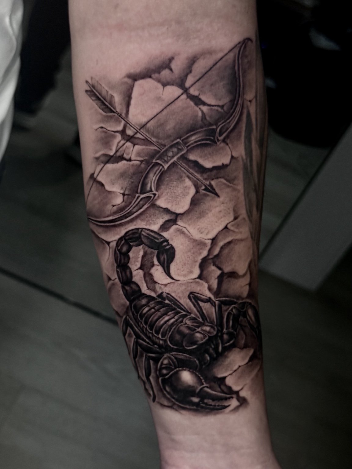 Black and grey scorpion, bow and arrow forearm tattoo by Alina Horobets, Bournemouth