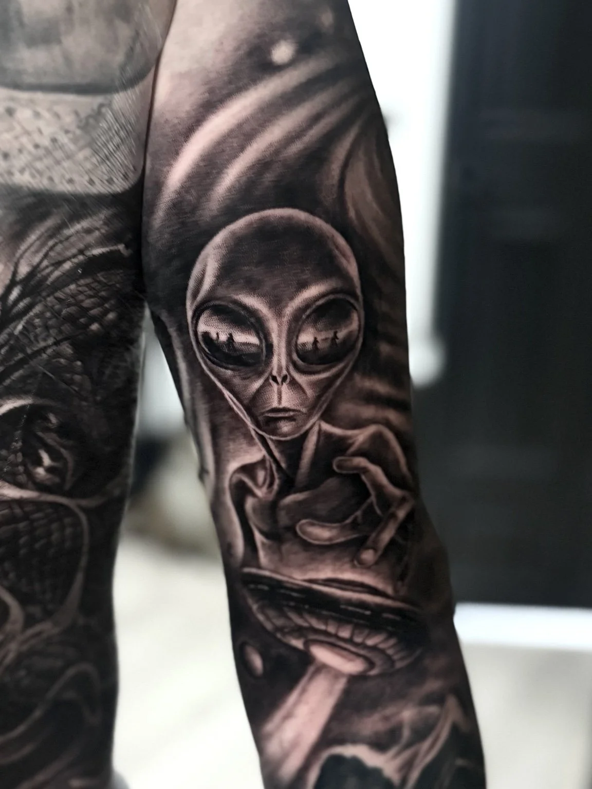 Black and grey alien and UFO realism tattoo by Alina Horobets, Bournemouth