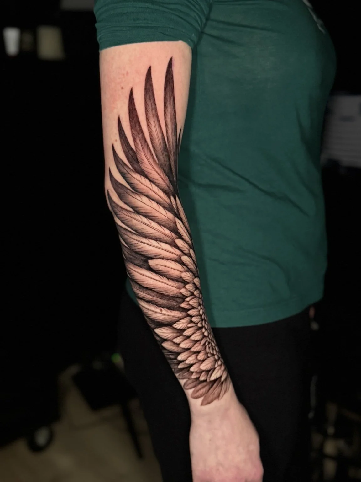 Detailed feather wing forearm tattoo by Alina Horobets, Bournemouth