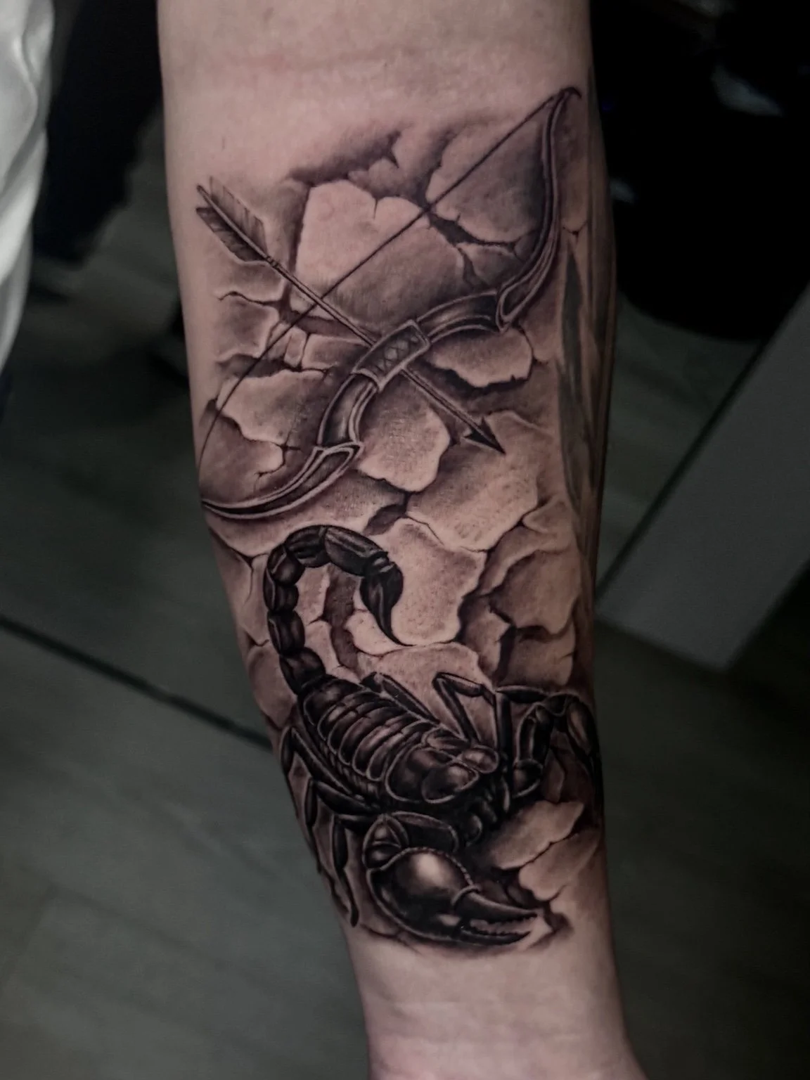 Black and grey scorpion, bow and arrow forearm tattoo by Alina Horobets, Bournemouth