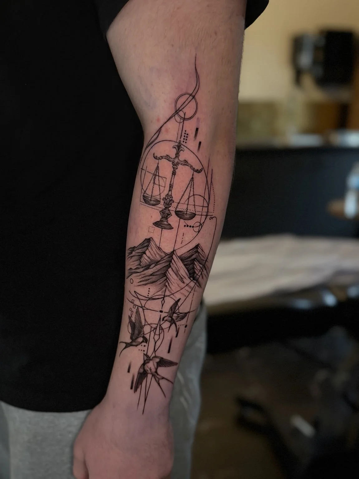 Fine line Lady Justice forearm tattoo with scales by Alina Horobets, Bournemouth