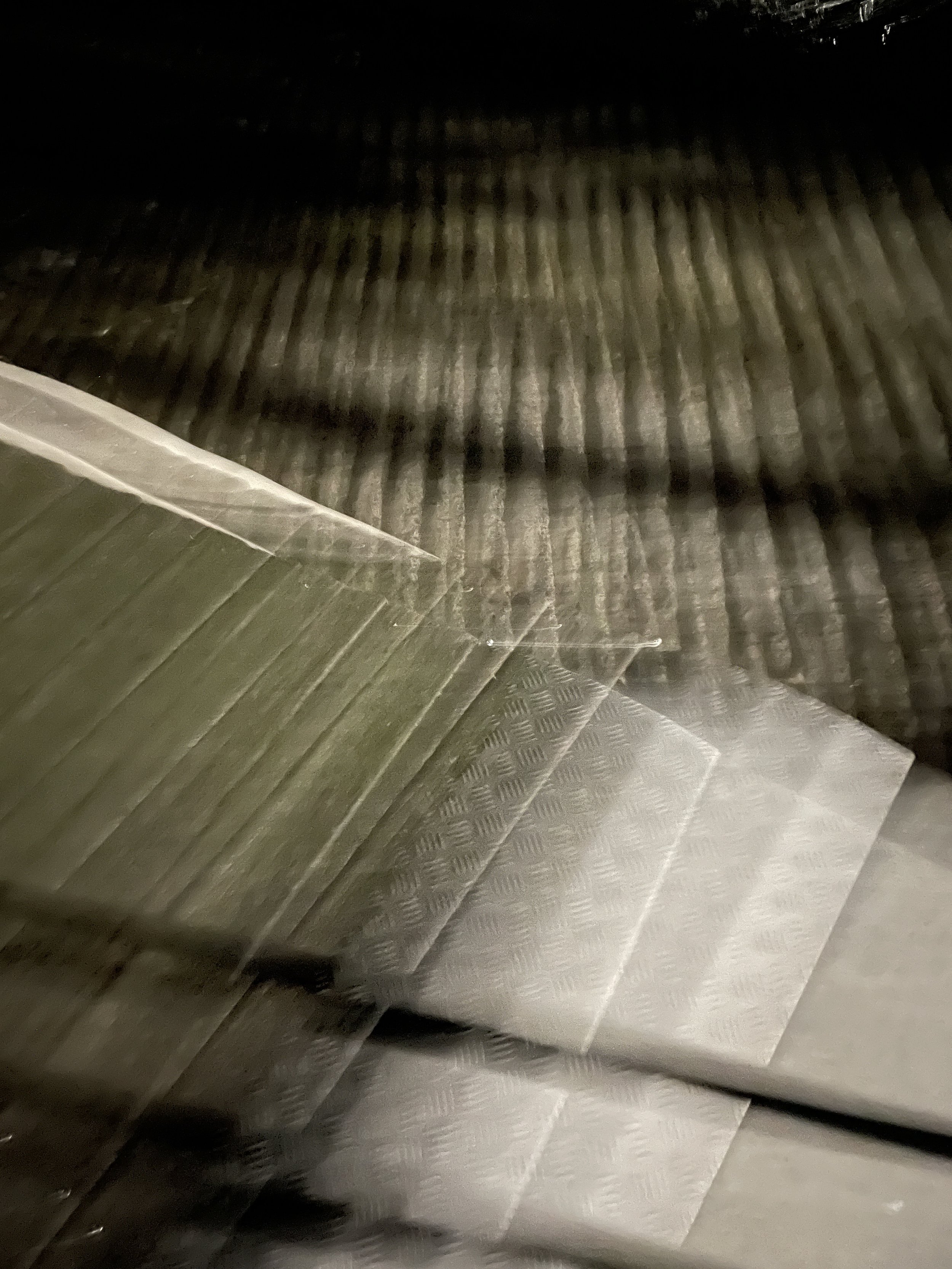 Close-up of a metallic, textured, ridged surface with overlapping material in a layered pattern.