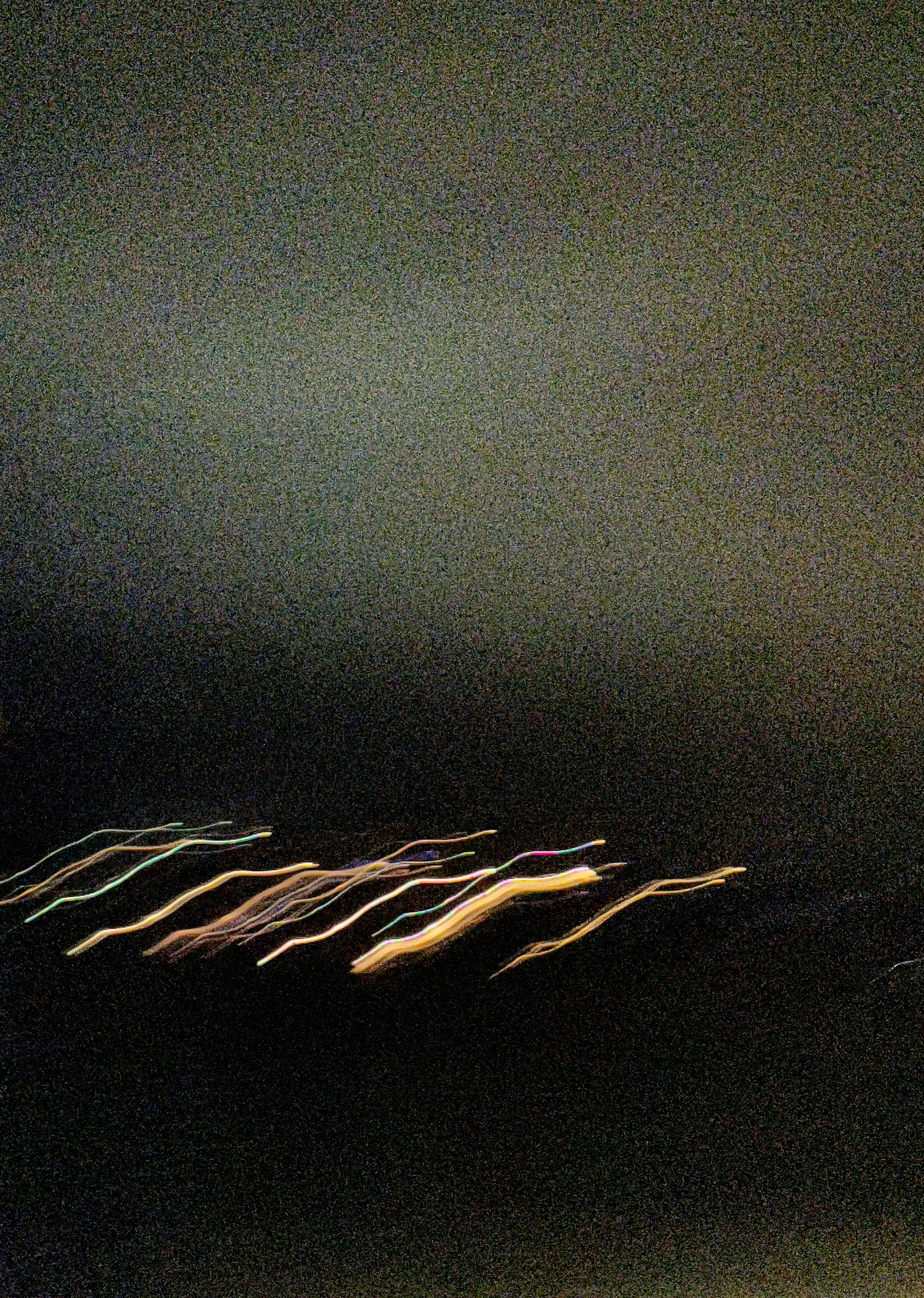 Nighttime city scene with streaks of colorful lights from moving vehicles on a dark road.