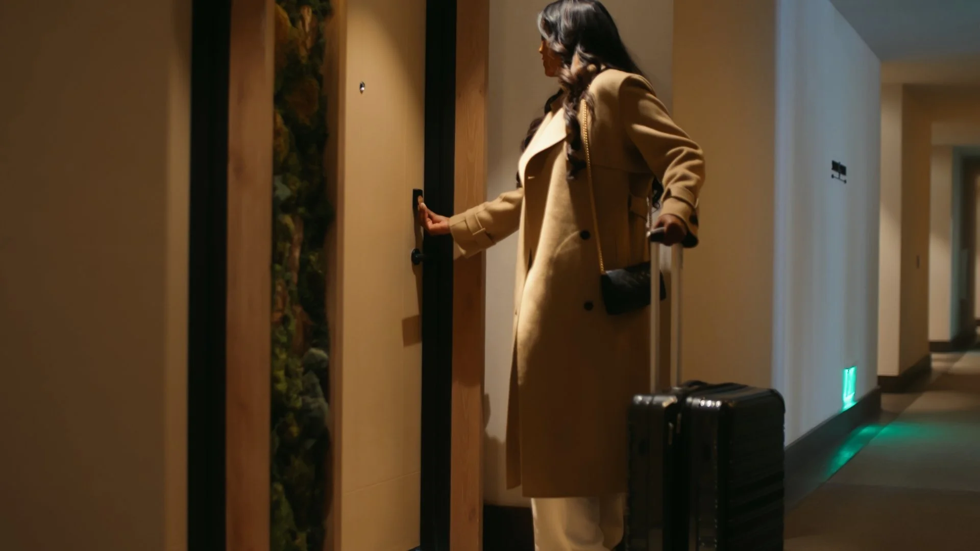 Hand holding a key card in front of an electronic door lock on a wooden surface