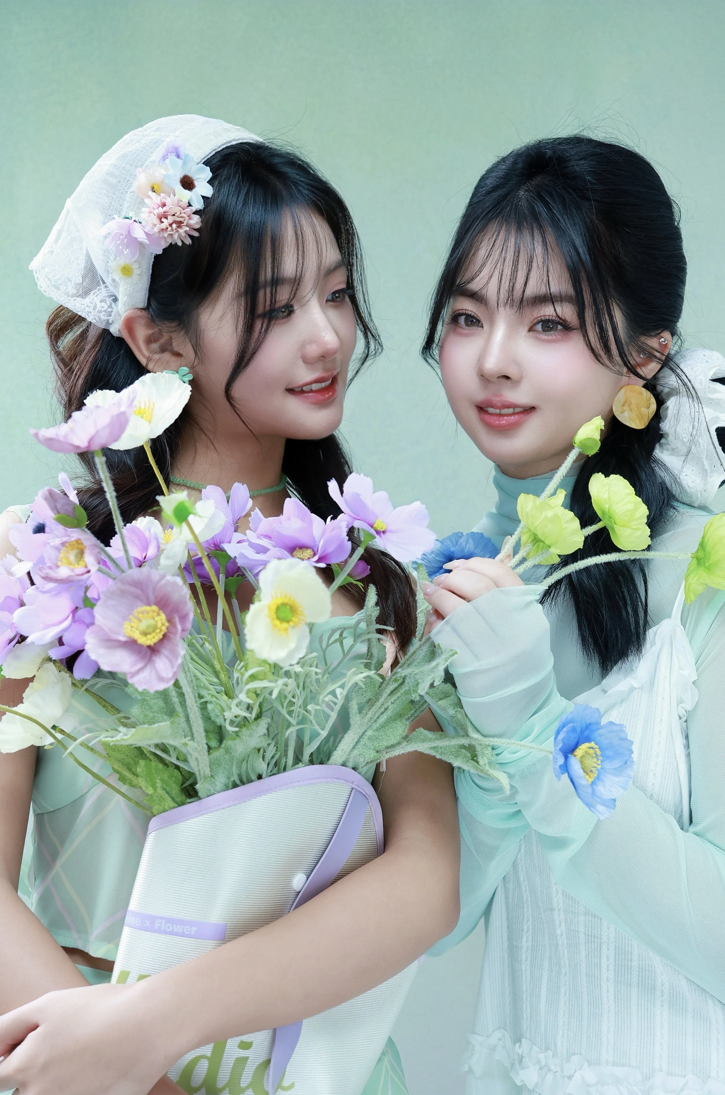 Two friends posing in a spring theme floral mint green studio one friend looking at the other friend