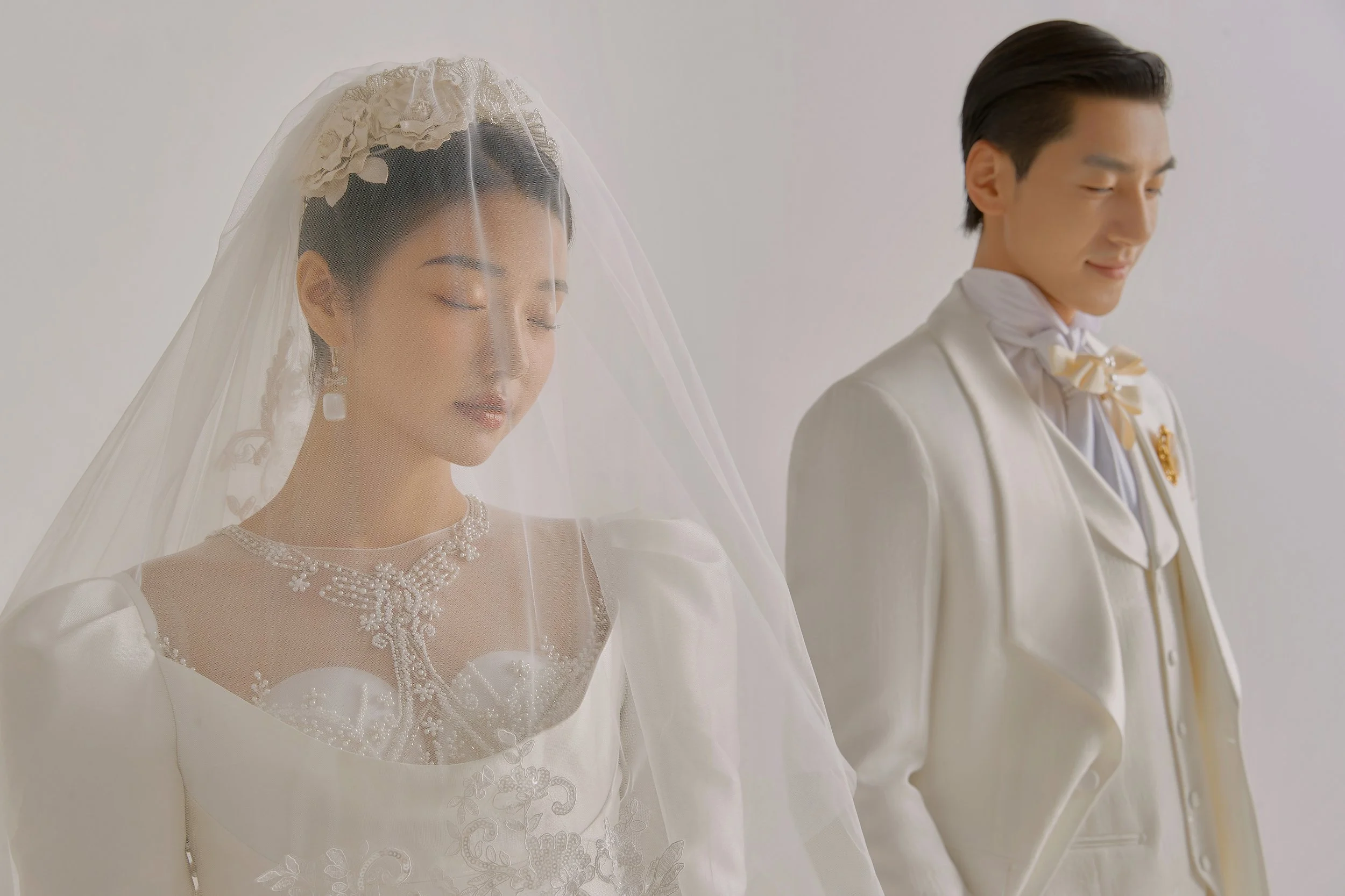 Romantic pre-wedding photoshoot of an Asian couple in full-white Western wedding dress and suit