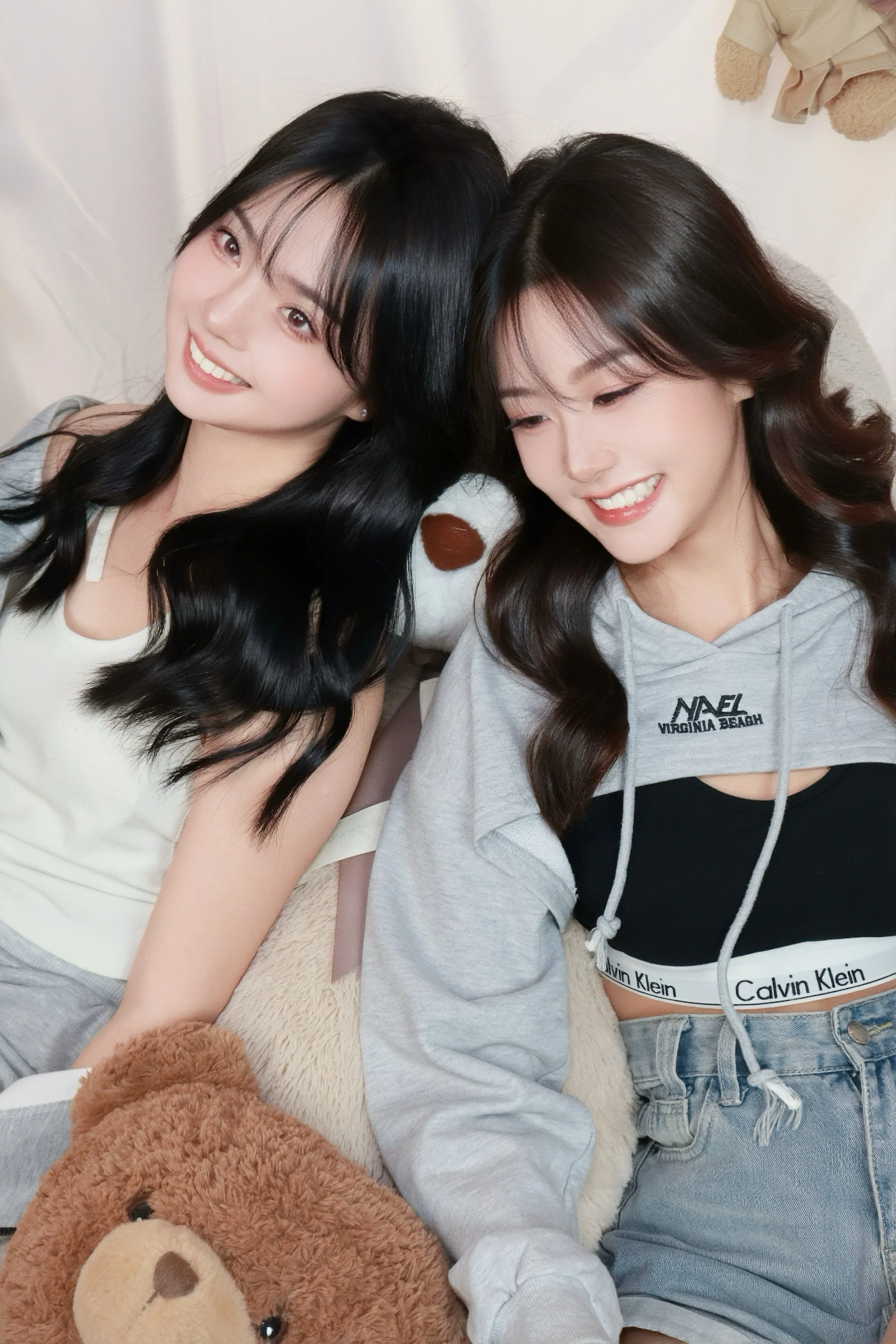 Two friends leaning against each other in comfy bedroom studio photoshoot