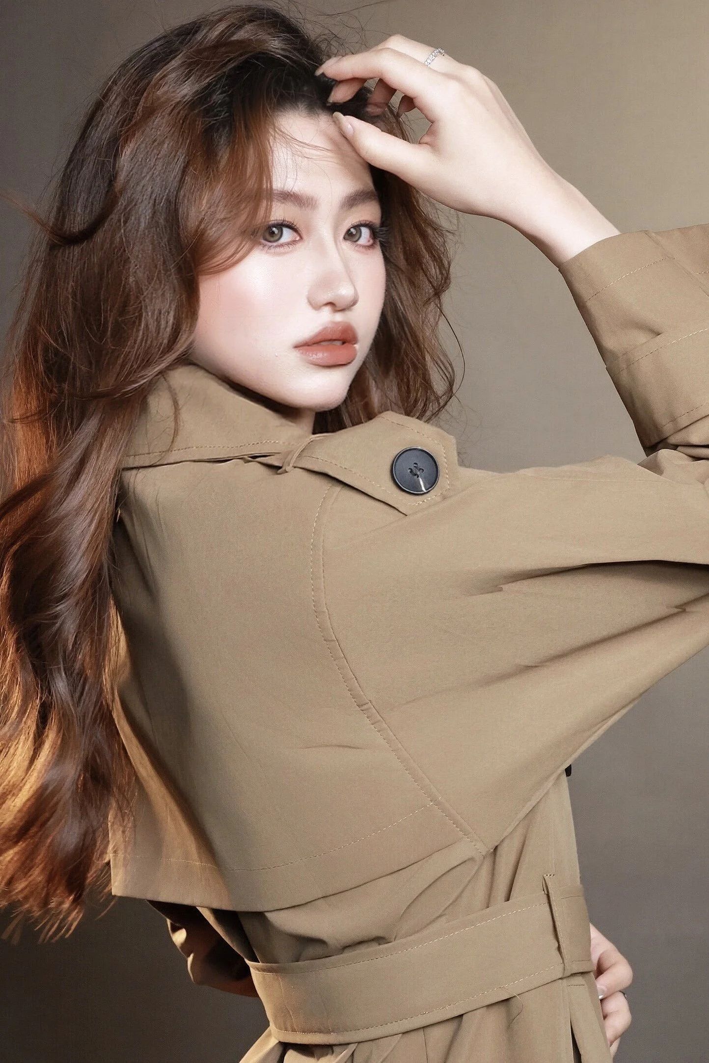Moody portrait of the side profile of a woman in a brown trench coat