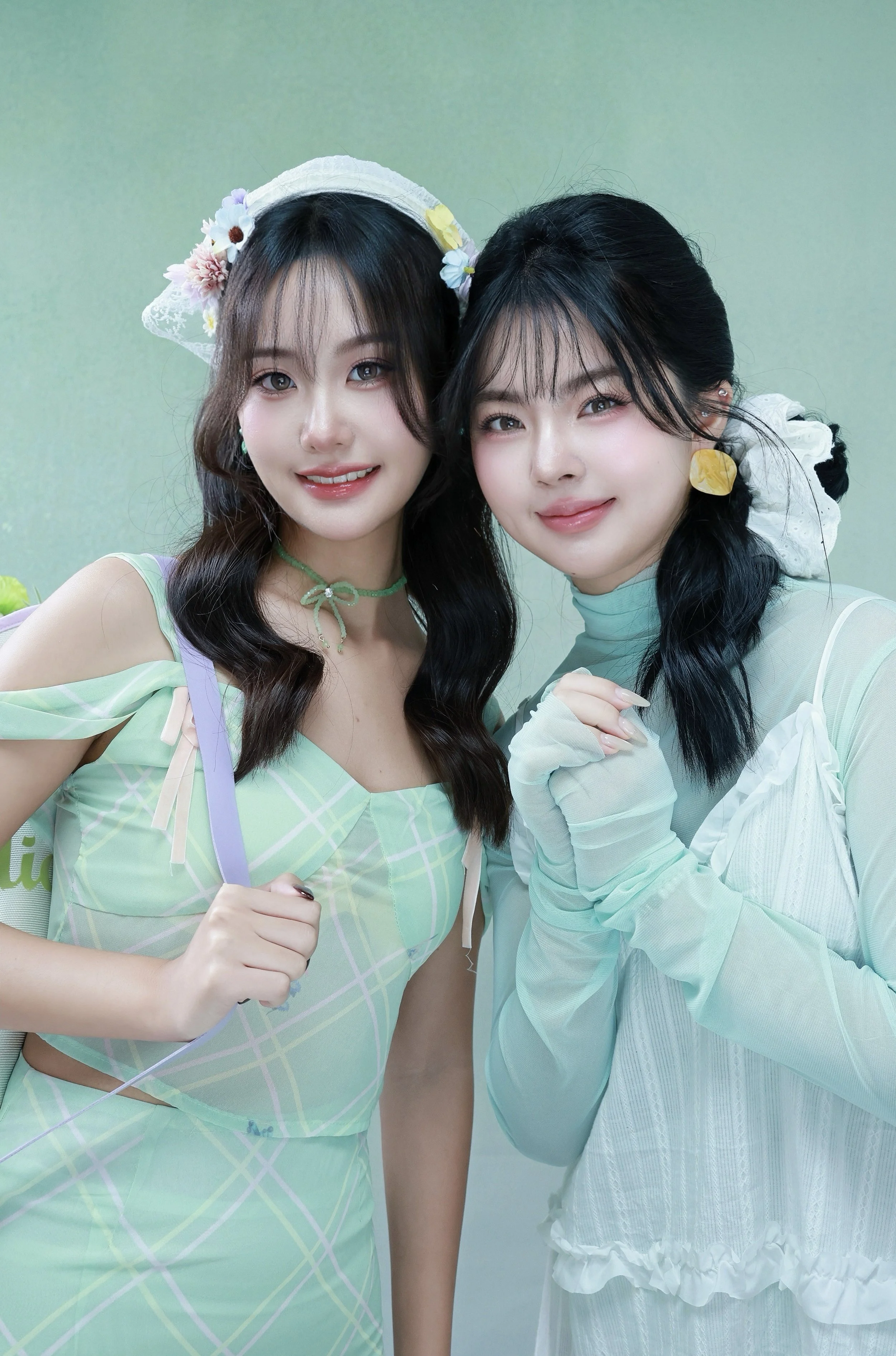 Two female friends posing in a studio photoshoot with mint green backdrop