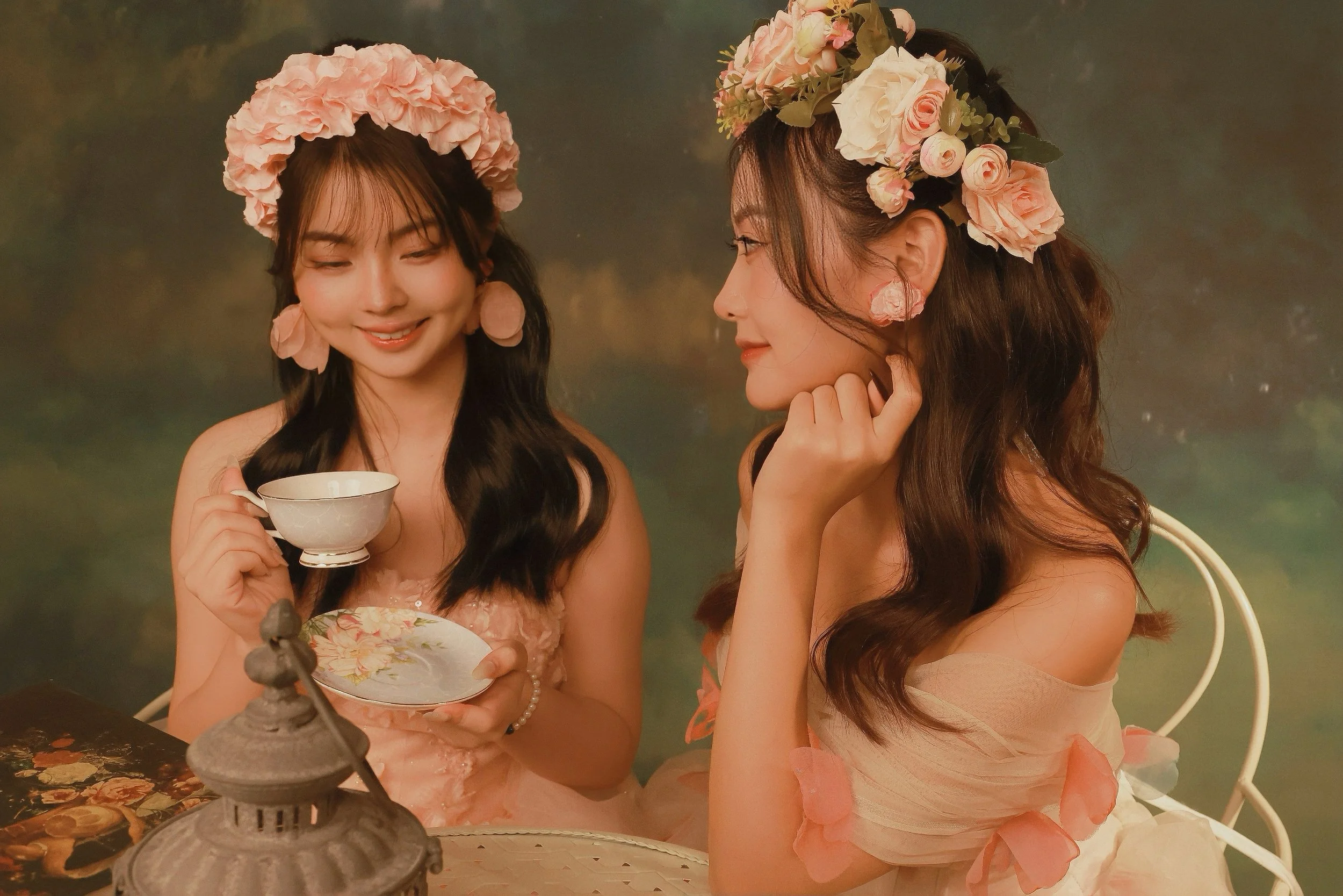 Two female friends in pink princess dresses having tea