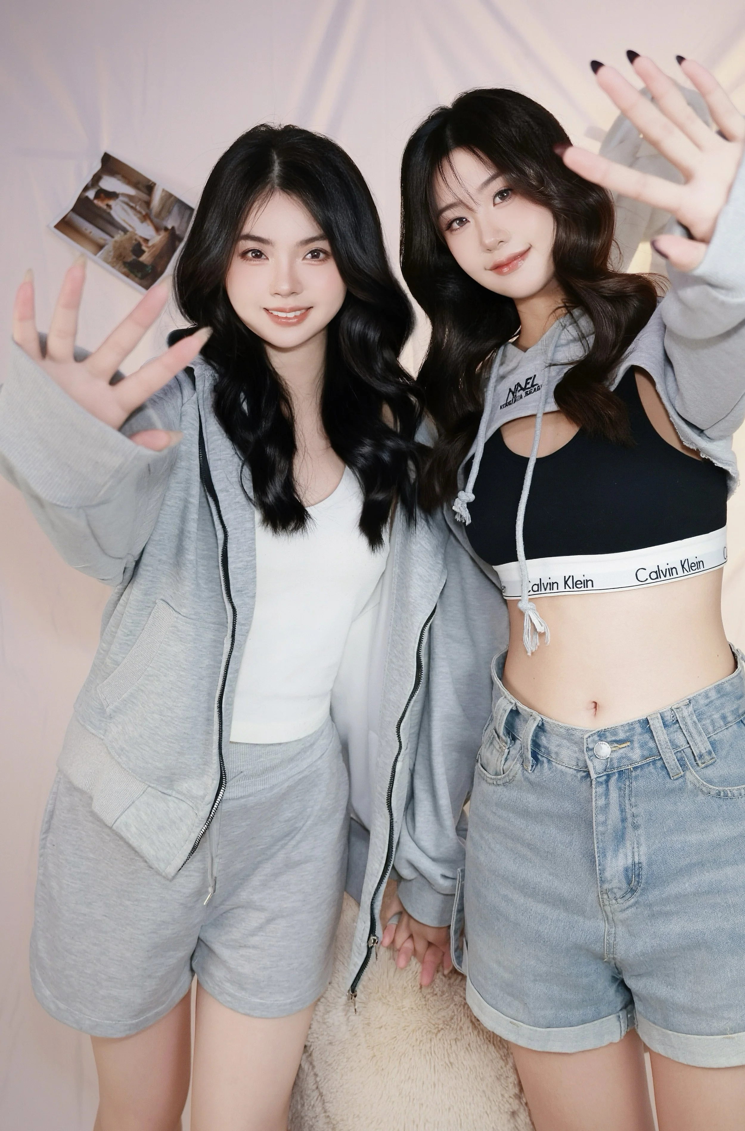 Two female friends in cozy hoodies with their hands stretched out facing the camera