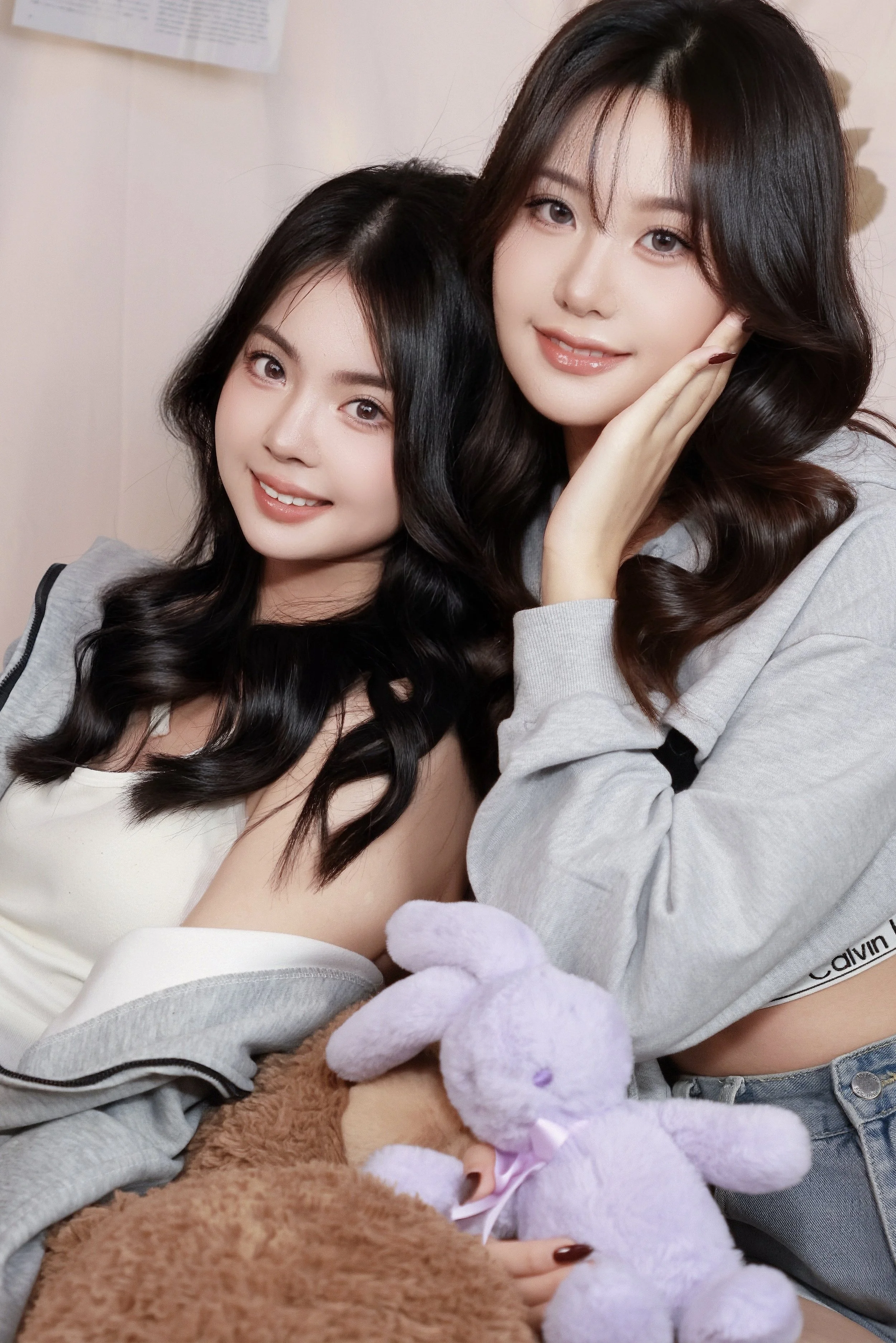 Two female friends posing snuggly together in cozy photoshoot