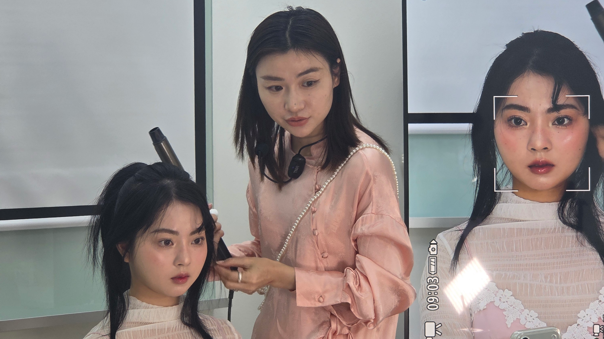 female makeup artist using curling iron to style girl model hair